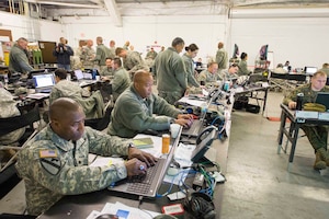U.S. Army Lt. Col. Dameion Logan (front), a member of the Joint Enabling Capabilities Command Joint Planning Support Element (JPSE), conducts business during U.S. Southern Command’s exercise Integrated Advance 2015 (IA-15). Various members of JPSE assumed critical positions on the Joint Task Force – Migrant Operations staff in the areas of operations, plans, logistics and knowledge management, while supporting IA-15 from Fort Sam Houston, Texas.