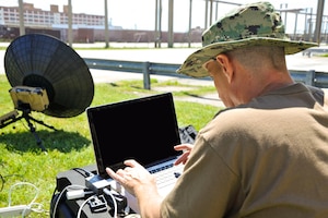 NORFOLK -- Chief Mass Communication Specialist Chris Fowler of Joint Public Affairs Support Element uses a laptop to connect a portable satellite dish used to transmit information to the Defense Video and Imagery Distribution System (DVIDS) during a Navy Reserve training weekend. The satellite system can be used in locations where access to traditional means of data transmission are not available. (U.S. Navy Photo by Mass Communication Specialist 2nd Class Christopher Lange/ RELEASED)
