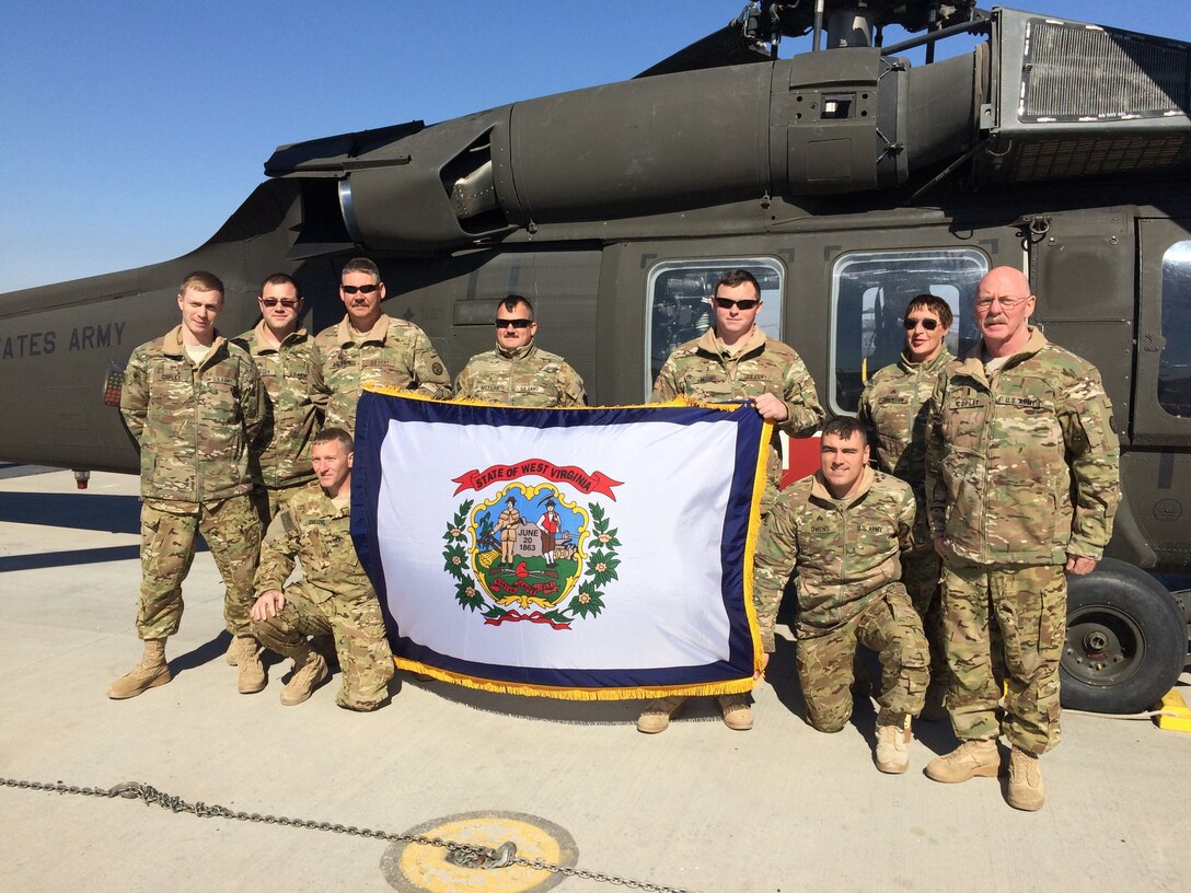 Chief Warrant Officer 4 Lawrence Copley, far right, and his son, Chief Warrant Officer 2 Joseph Copley, far left -- both Army National Guardsmen -- pose for a photo with soldiers from 2nd Battalion, 104th Aviation Regiment, 40th Combat Aviation Brigade, shortly after Joseph’s promotion at Camp Buehring Kuwait, Jan. 30, 2016. The Copleys deployed with the 40th CAB to Kuwait in December 2015. Courtesy photo