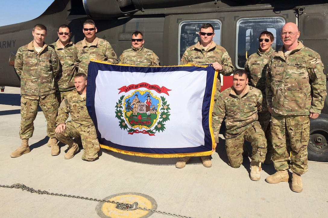 Chief Warrant Officer 4 Lawrence Copley, far right, and his son, Chief Warrant Officer 2 Joseph Copley, far left -- both Army National Guardsmen -- pose for a photo with soldiers from 2nd Battalion, 104th Aviation Regiment, 40th Combat Aviation Brigade, shortly after Joseph’s promotion at Camp Buehring Kuwait, Jan. 30, 2016. The Copleys deployed with the 40th CAB to Kuwait in December 2015. Courtesy photo