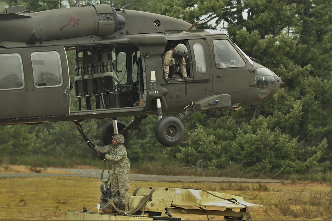 A soldier hooks communication equipment to a UH-60 Black Hawk helicopter during slingload and air assault training on Joint Base Lewis-McChord, Wash., Feb. 10, 2016. Army photo by Capt. Brian Harris