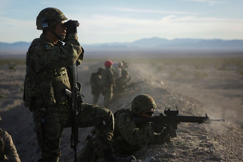 A rifleman assigned to Western Army Infantry Regiment, Japan Ground Self Defense Force, observes the impact area as several service members fire on simulated targets, during a live-fire platoon level assault, during Exercise Iron Fist 2016 aboard Marine Corps Air Ground Combat Center Twentynine Palms, Feb. 9, 2016. Iron Fist is an annual, bi-lateral training exercise between the Japan Ground Self Defense Force and Marines to strengthen warfighting capabilities in ship to shore operations.