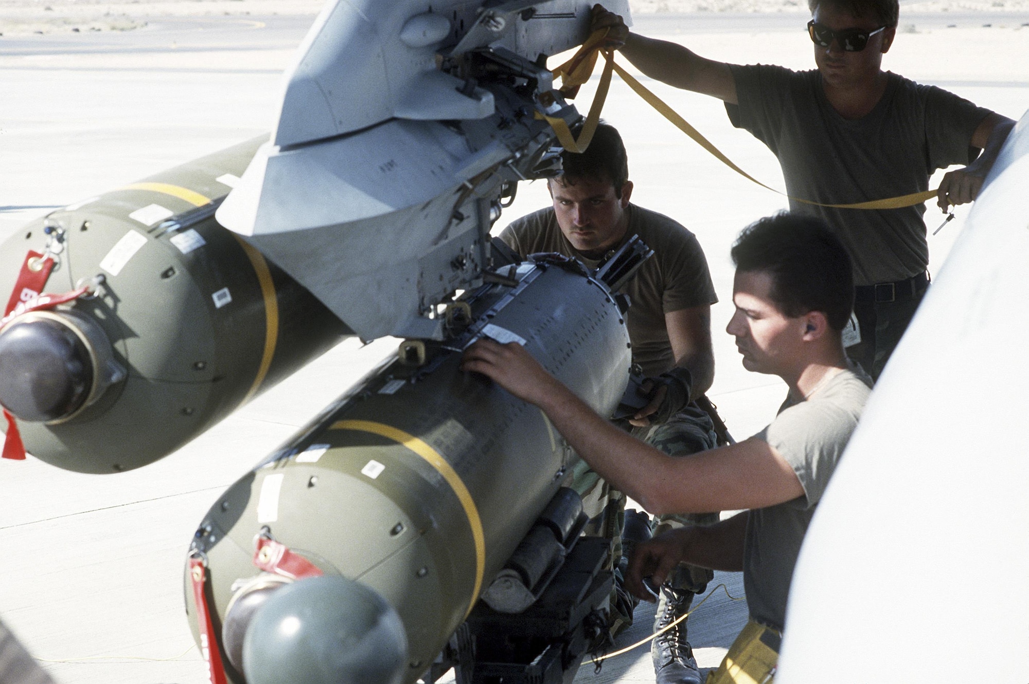 Members of the 4th Weapons Squadron load SUU-65/B tactical munitions dispensers onto an aircraft as they ready it for a mission during Operation Desert Shield. (U.S. Air Force photo)