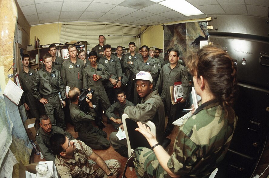 Tech. Sgt. Tony Tesori, right, weather forecaster, Detachment 6, 17th Weather Squadron, Hill Air Force Base, Utah, briefs aircrews on local and Iraqi weather conditions during Operation Desert Storm. (U.S. Air Force photo)