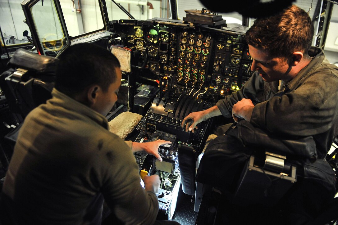 Air Force Senior Airman Kendren Reyes, left, and Air Force Staff  Sgt. Jake Lucht examine a panel on the flight deck of the EC-130 Compass Call on Bagram Airfield, Afghanistan, Feb. 10, 2016. Reyes is a communications navigation journeyman and Lucht is a crew chief assigned to the 455th Expeditionary Aircraft Maintenance Squadron. Air Force photo by Tech. Sgt. Nicholas Rau