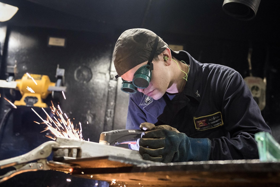 Navy Petty Officer 2nd Class Christian Carbonetto cuts metal with a plasma saw in the sheet metal shop aboard the USS Harry S. Truman in the Arabian Sea, Feb. 18, 2016. Navy photo by Seaman Adelola O. Tinubu