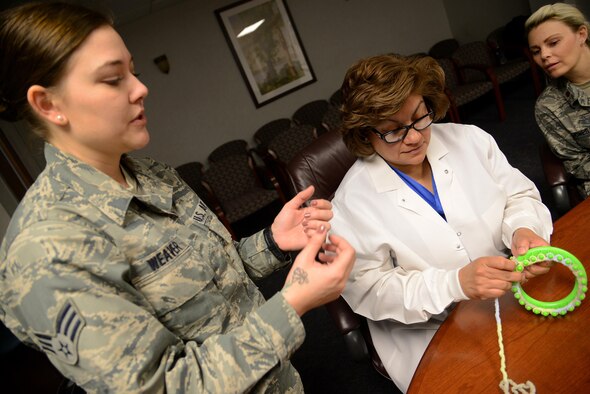 Senior Airman Chey Weaver, 47th Medical Support Squadron biomedical equipment repair technician, instructs Rita Riojas, 47th Medical Operations Squadron dental assistant, during a Heartstrings “lunch-n-loom” session at Laughlin Air Force Base, Texas, Jan. 21, 2016. Heartstrings is a program started by two Airmen who teach attendees to crochet knit baby hats. (U.S. Air Force photo by Senior Airman Ariel D. Partlow)