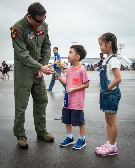 Maj. Austin Brown, an F-16 pilot with the Pacific Air Forces Aerial Demonstration Team, gives a sticker to a young fan during the Singapore International Airshow, at Changi International Airport, Singapore, Feb. 20, 2016. The show is focused on building strong relations between Singapore, U.S. and the international community. (U.S. Air Force photo by Capt. Raymond Geoffroy/Released)