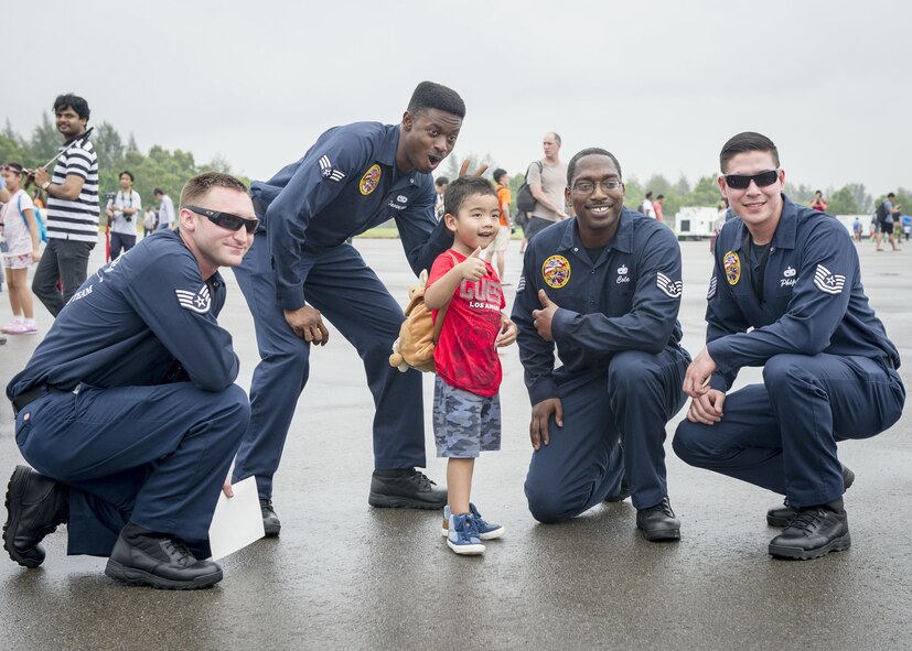 Maintainers from the Pacific Air Forces Aerial Demonstration Team pose for a photo with a young fan during the Singapore International Airshow, at Changi International Airport, Singapore, Feb. 20, 2016. The show is focused on building strong relations between Singapore, U.S. and the international community. (U.S. Air Force photo by Capt. Raymond Geoffroy/Released)