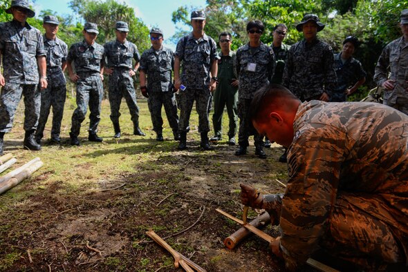 Staff Sgt. Levi Wood, survival, evasion, resistance and escape instructor assigned to the 353rd Combat Training Squadron, shows visiting Japan Air Self-Defense Force airmen how to safely split bamboo to start a fire Feb. 16, 2016, at Andersen Air Force Base, Guam. Exercise Cope North 16 includes 22 total flying units and nearly 3,000 personnel from six countries and continues the growth of strong, interoperable and beneficial relationships within the Indo-Asia-Pacific Region through integration of airborne and land-based command and control assets. (U.S. Air Force photo by Staff Sgt. Alexander W. Riedel/Released)