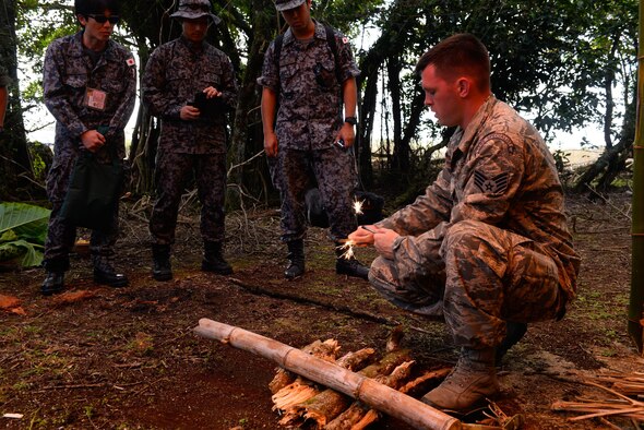 Staff Sgt. Levi Wood, a survival, evasion, resistance and escape instructor assigned to the 353rd Combat Training Squadron, shows visiting Japan Air Self-Defense Force airmen how to safely start a fire using fire steel Feb. 16, 2016, at Andersen Air Force Base, Guam. Exercise Cope North 16 includes 22 total flying units and nearly 3,000 personnel from six countries and continues the growth of strong, interoperable and beneficial relationships within the Indo-Asia-Pacific Region through integration of airborne and land-based command and control assets. (U.S. Air Force photo by Staff Sgt. Alexander W. Riedel/Released)