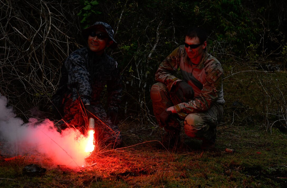 Master Sgt. Kurt Douge, the superintendent of the personnel recovery division at the 353rd Combat Training Squadron, right, demonstrates how to use a signal flare to Japan Air Self-Defense Force pararescueman Tech. Sgt. Shinichiro Sasaki during a jungle survival workshop Feb. 16, 2016, at Andersen Air Force Base, Guam. Exercise Cope North 16 includes 22 total flying units and nearly 3,000 personnel from six countries and continues the growth of strong, interoperable and beneficial relationships within the Indo-Asia-Pacific region through integration of airborne and land-based command and control assets. (U.S. Air Force photo by Staff Sgt. Alexander W. Riedel/Released)