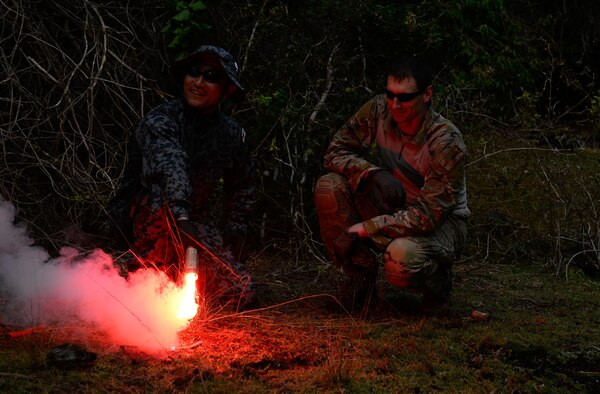 Master Sgt. Kurt Douge, the superintendent of the personnel recovery division at the 353rd Combat Training Squadron, right, demonstrates how to use a signal flare to Japan Air Self-Defense Force pararescueman Tech. Sgt. Shinichiro Sasaki during a jungle survival workshop Feb. 16, 2016, at Andersen Air Force Base, Guam. Exercise Cope North 16 includes 22 total flying units and nearly 3,000 personnel from six countries and continues the growth of strong, interoperable and beneficial relationships within the Indo-Asia-Pacific region through integration of airborne and land-based command and control assets. (U.S. Air Force photo by Staff Sgt. Alexander W. Riedel/Released)