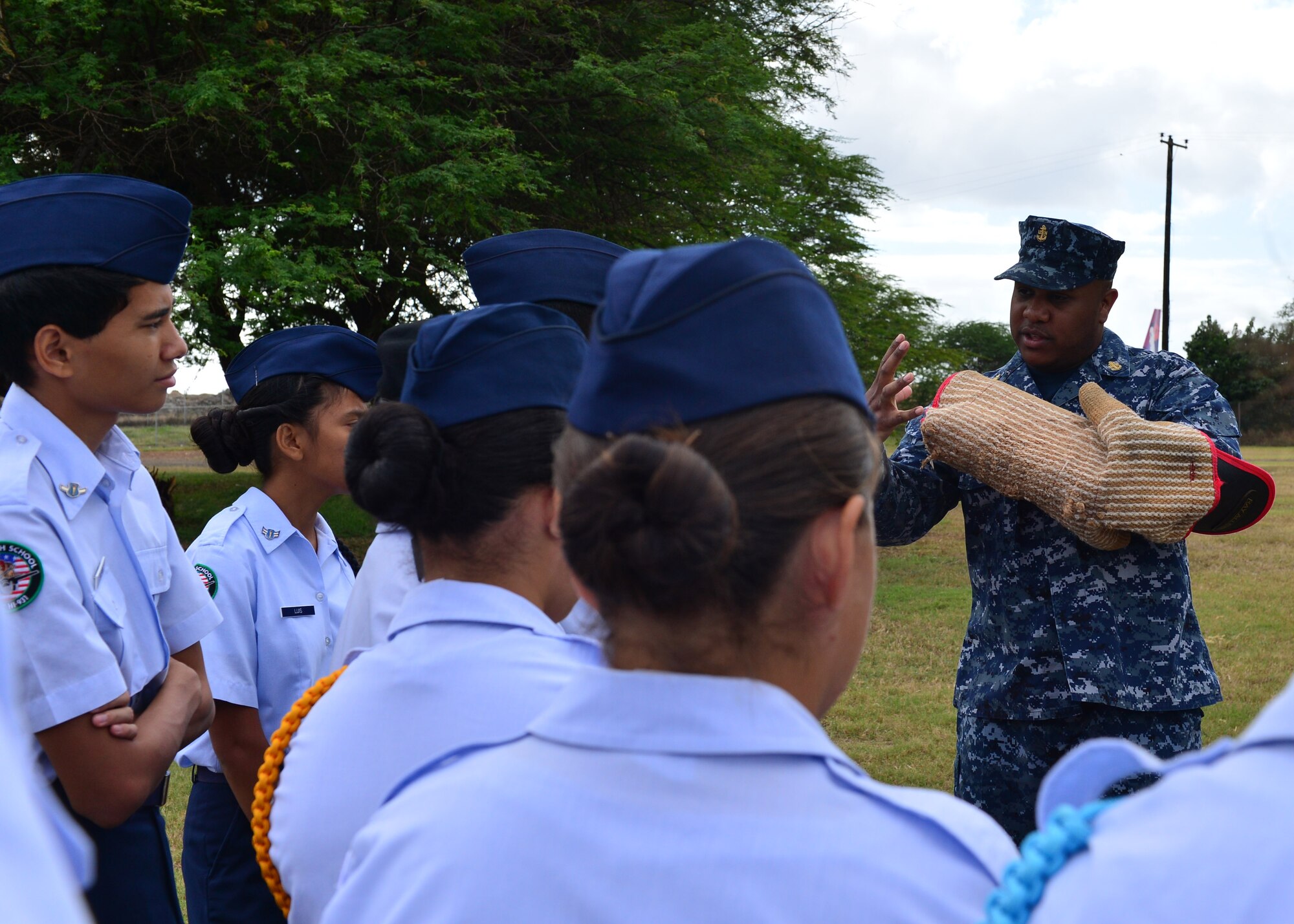 Chief Petty Officer Marc Jones, from the 647th Security Forces Squadron, demonstrates how a bite sleeve is used to train military working dogs to students from Aiea High School’s Air Force Junior Reserve Officer Training Corps on Joint Base Pearl Harbor-Hickam, Hawaii, Feb 18, 2016. The 30 JROTC students toured a C-17 Globemaster III and visited the 647th Explosive Ordnance Disposal unit and the 647th Security Forces Squadron's military working dog kennel during their visit to JBPHH. (U.S. Air Force photo by Tech. Sgt. Aaron Oelrich/Released) 