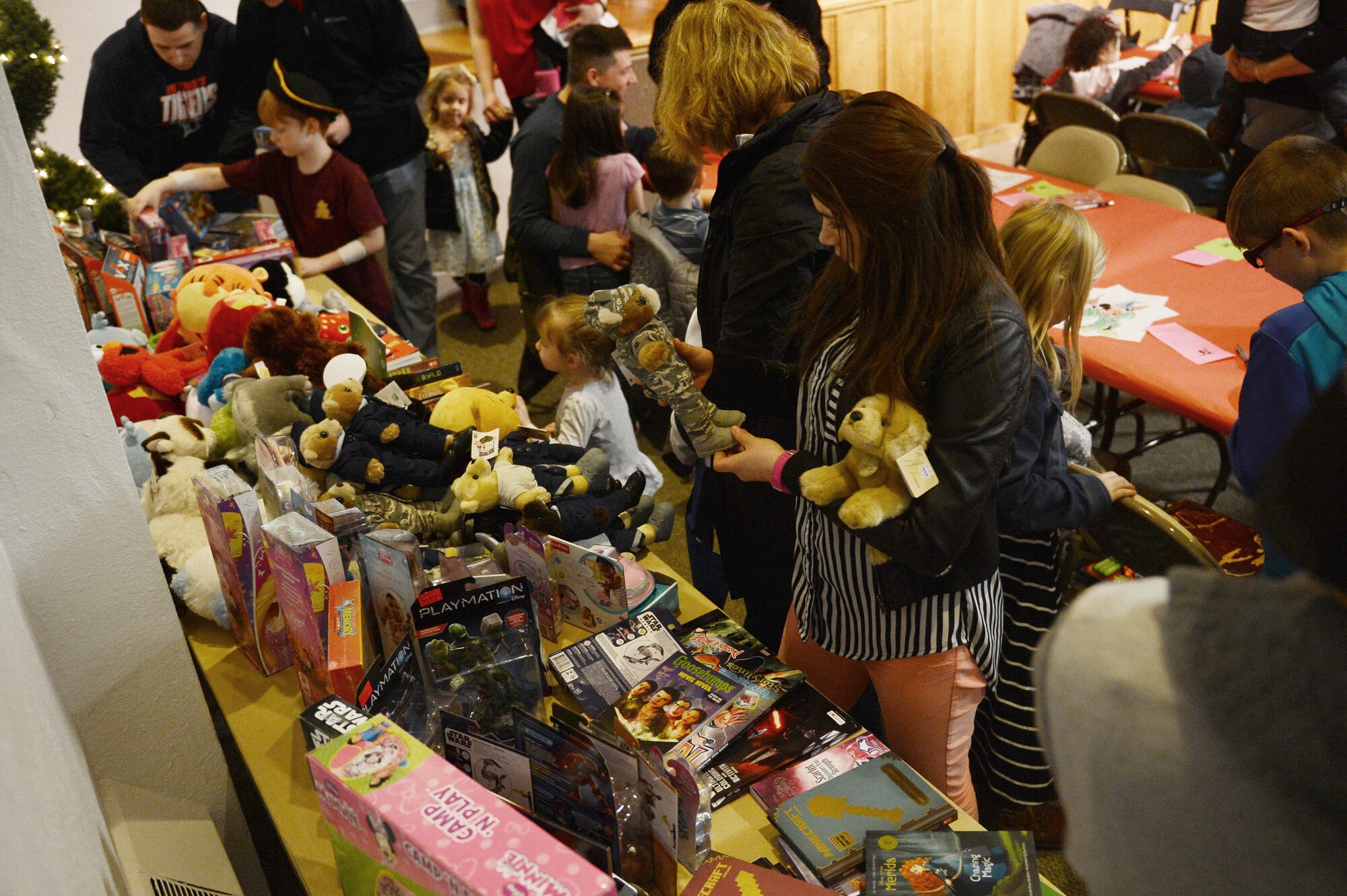 Children of deployed service members, pick toys off a table during the Team McChord Deployed Family Dinner Feb. 19, 2016 at the Chapel Support Center on Joint Base Lewis-McChord, Wash. The children got the opportunity to pick out toys and interact with two magicians who walked around doing magic. (U.S. Air Force photo/Senior Airman Divine Cox)