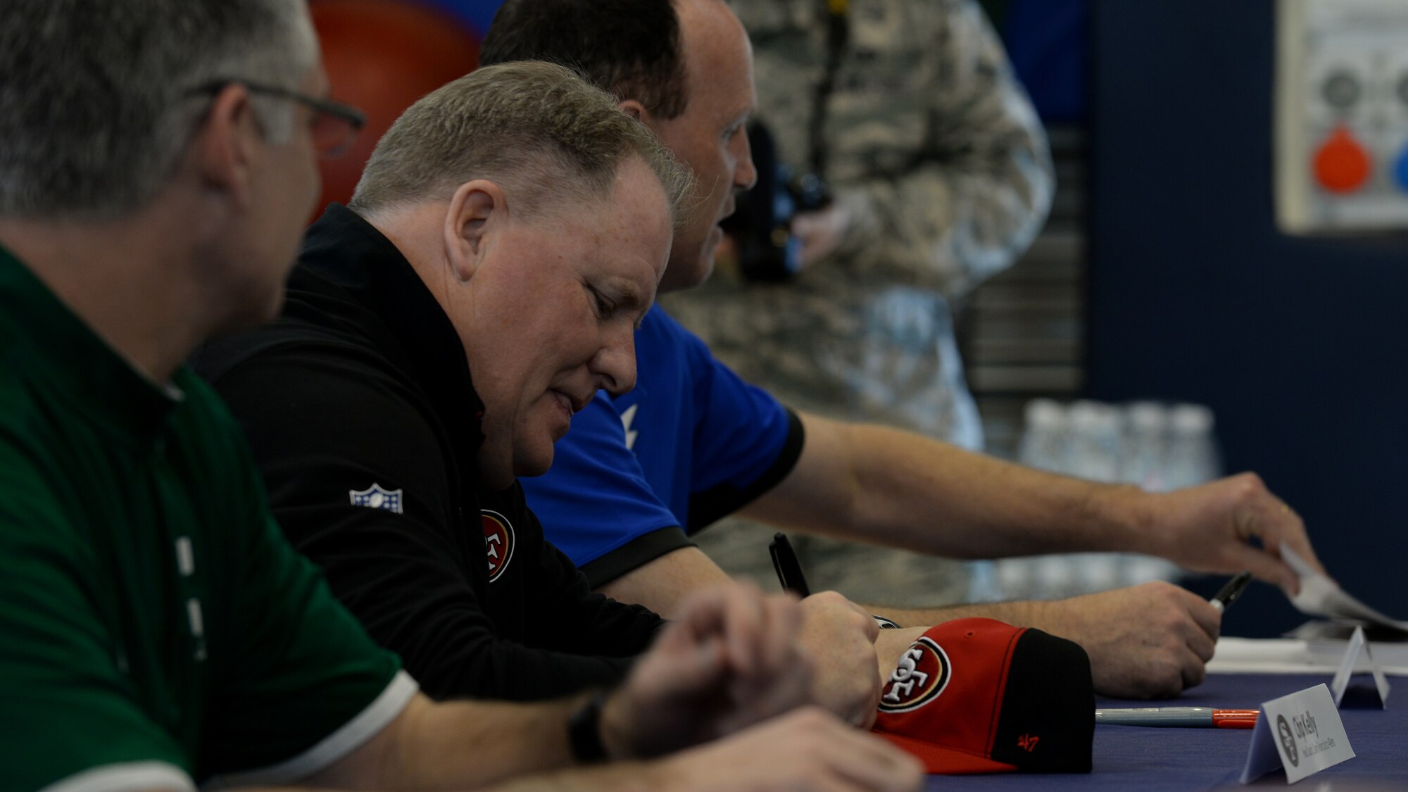 Chip Kelly, San Francisco 49ers head coach, signs a sports cap during the 2016 Coaches Tour, Feb. 18, 2016, at Aviano Air Base, Italy. The coaches met with Team Aviano members to answer questions and host a mock football combine. (U.S. Air Force photo by Airman 1st Class Cary Smith/Released)