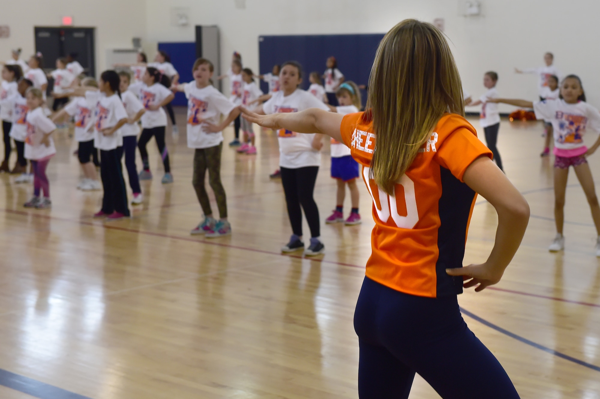 A Denver Broncos cheerleader leads a choreographed dance at the Buckley Youth Center Feb. 20, 2016, on Buckley Air Force Base, Colo. The cheerleaders held a cheer clinic as part of an initiative to increase opportunities for military youth to participate in fitness programs which was coordinated by the Buckley Youth Center along with the Broncos organization. The Air Force Services Agency Child and Youth Programs helped fund the clinic, which 65 children between the ages of 6 and 18 took part in.  (U.S. Air Force photo by Airman 1st Class Luke W. Nowakowski/Released)