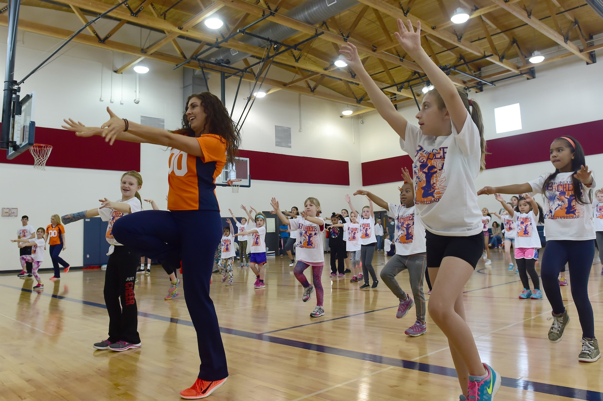 A Denver Broncos cheerleader leads a choreographed dance at the Buckley Youth Center Feb. 20, 2016, on Buckley Air Force Base, Colo.  The cheerleaders held a cheer clinic as part of an initiative to increase opportunities for military youth to participate in fitness programs which was coordinated by the Buckley Youth Center along with the Denver Broncos organization. The Air Force Services Agency Child and Youth Programs helped fund the clinic, which 65 children between the ages of 6 and 18 took part in.  (U.S. Air Force photo by Airman 1st Class Luke W. Nowakowski/Released)
