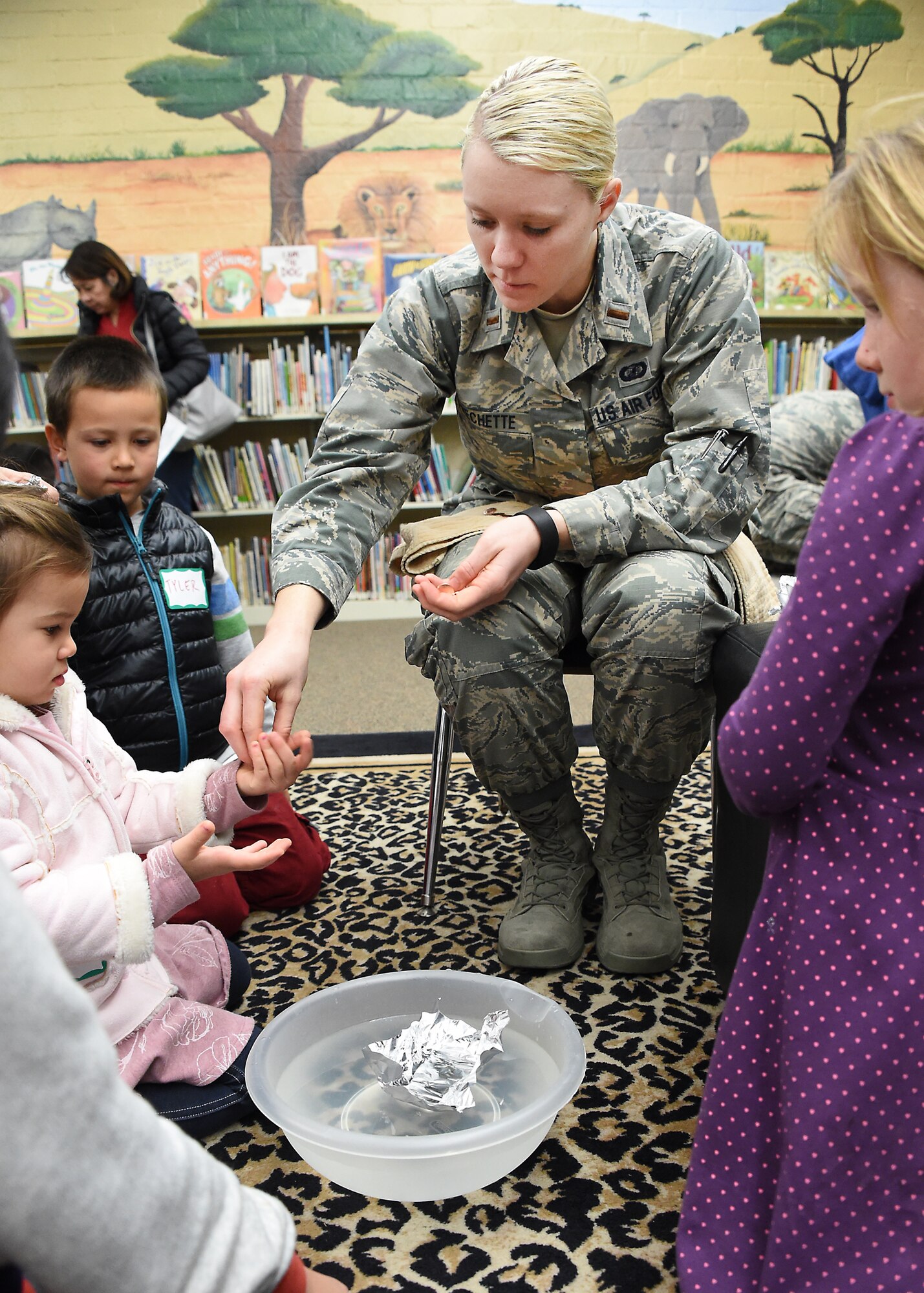 U.S. Air Force 2nd Lt. Megan Frechette hands out pennies in the “Aluminum Foil Boats” demonstration, where students fashioned a boat out of foil and inserted pennies to see who could float the most pennies while learning about design and displacement. Thirty-seven volunteers from Los Angeles Air Force Base, El Segundo, Calif., visited Center Elementary School in El Segundo to staff various STEM (Science Technology Engineering Mathematics) experiment stations led by the Space and Missile Systems Center volunteers, where they work with the students at the Engineering/Building Stations and Food Science Experiment Stations to collect and discuss observed results, Feb 3, 2015 (U. S. Air Force photo Joseph M. Juarez Sr) 