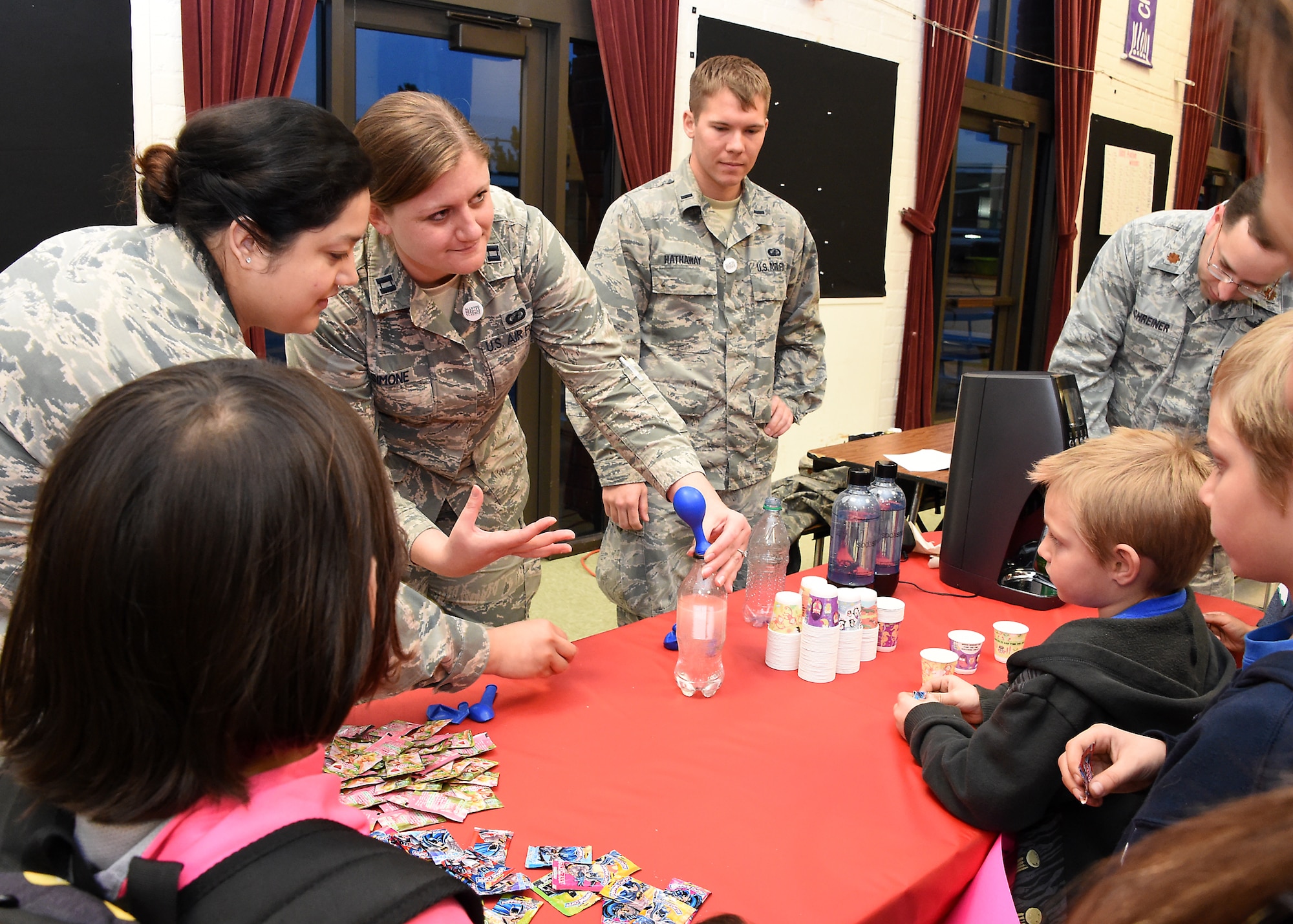 U.S. Air Force Tech. Sgt. Francis Osorio, (left to right) Capt. Rachel Simone, 1st Lt. Kyle Hathaway and Maj. Michael Schreiner operate the Food Science table to experiment with pressurized carbon dioxide, demonstrated by filling the balloon. Thirty-seven volunteers from Los Angeles Air Force Base, El Segundo, Calif., visited Center Elementary School in El Segundo to staff various STEM (Science Technology Engineering Mathematics) experiment stations led by the Space and Missile Systems Center volunteers, where they work with the students at the Engineering/Building Stations and Food Science Experiment Stations to collect and discuss observed results, Feb 3, 2015 (U. S. Air Force photo Joseph M. Juarez Sr)