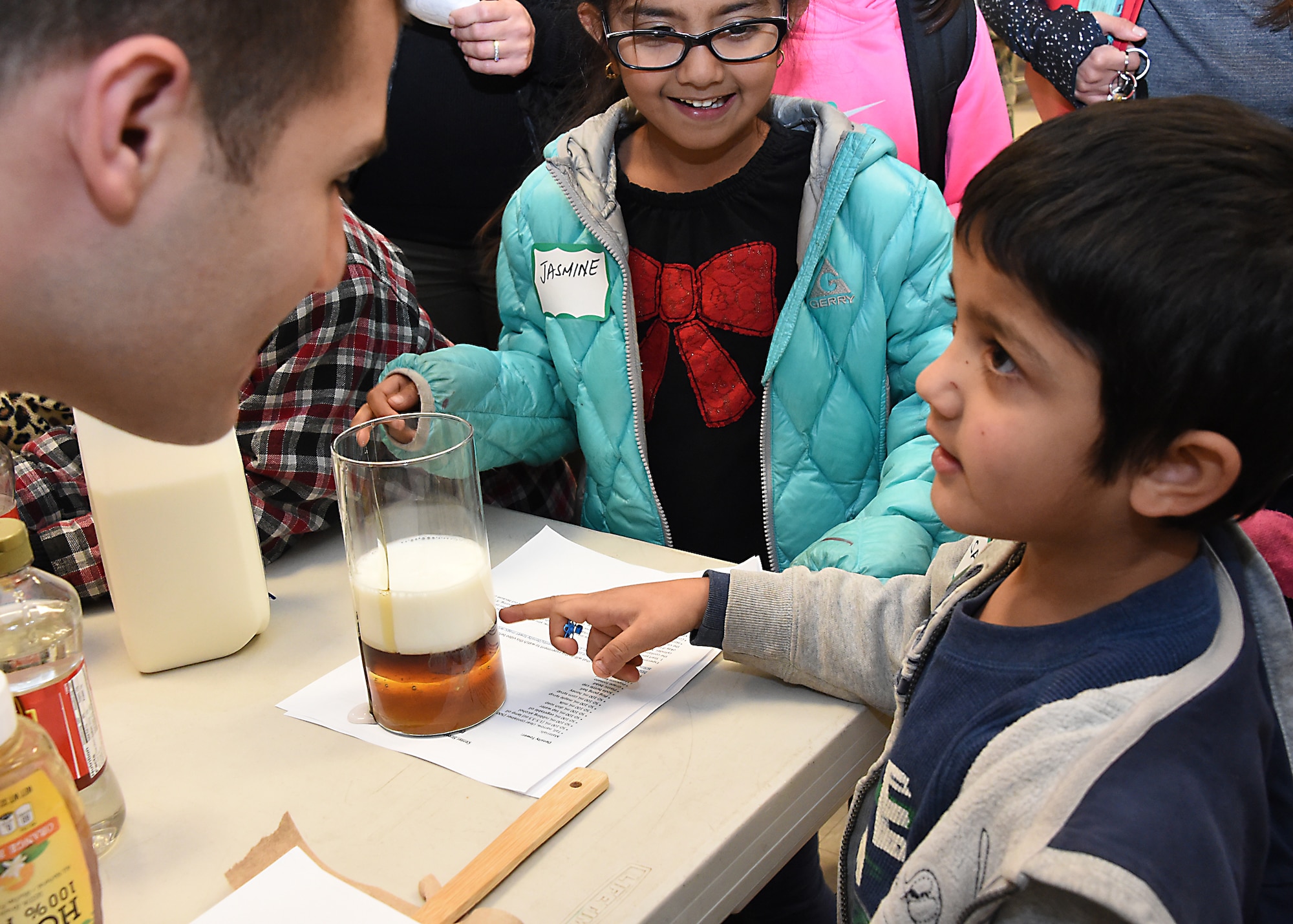 U.S. Air Force 1st Lt. Rinaldo Izzo pours milk and various other liquids to demonstrate and discuss the definition and relationship of density (mass/volume) with grade school students. Thirty-seven volunteers from Los Angeles Air Force Base, El Segundo, Calif., visited Center Elementary School in El Segundo to staff various STEM (Science Technology Engineering Mathematics) experiment stations led by the Space and Missile Systems Center volunteers, where they work with the student at the Engineering/Building Stations and Food Science Experiment Stations to collect and discuss observed results, Feb 3, 2015 (U. S. Air Force photo Joseph M. Juarez Sr)