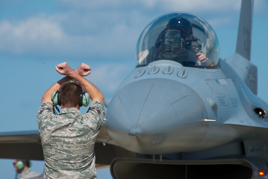 Senior Airman Larry Runk, of the 158th Maintenance Squadron, marshals an F-16 Fighting Falcon from the flight line during operation Combat Hammer at Eglin Air Force Base, Fla., Feb. 8, 2016. Combat Hammer is a Weapon System Evaluation Program that evaluates the effectiveness of precision guided munitions when employed in air-to-ground combat. (U.S. Air Force photo by Airman 1st Class Jeffrey Tatro)