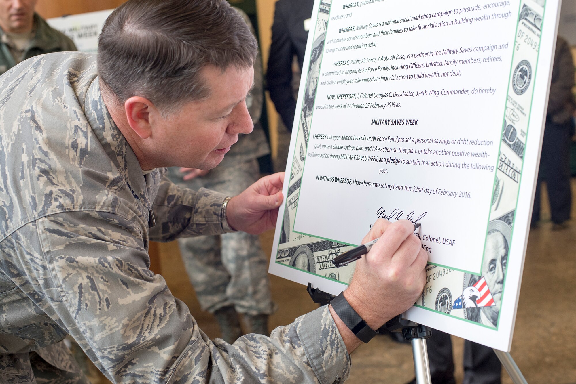 Col. Neil Richardson, 374th Airlift Wing vice commander, signs the proclamation officially kicking off Military Saves Week at Yokota Air Base, Japan, Feb. 22, 2016. Since the launch of Military Save Week in 2007, over 200,000 individuals have taken the saver pledge. (U.S. Air Force photo by Senior Airman David C. Danford/Released)
