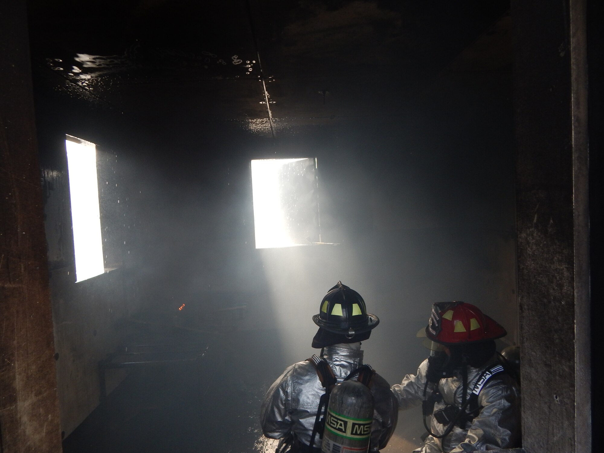 SOTO CANO AIR BASE, Honduras –Firefighters with, the 612th Air Base Squadron, finish putting out a fire in a burn house during a familiarization and proficiency exercise, Feb. 18, 2016, at Soto Cano Air Base, Honduras. These exercises test skills needed to respond to various scenarios, including structural fires like this one, and occur on a regular basis, honing  firefighters’ skills to detect flaws and make improvements in their abilities. (U.S. Army photo by Spc. Audie Colón)