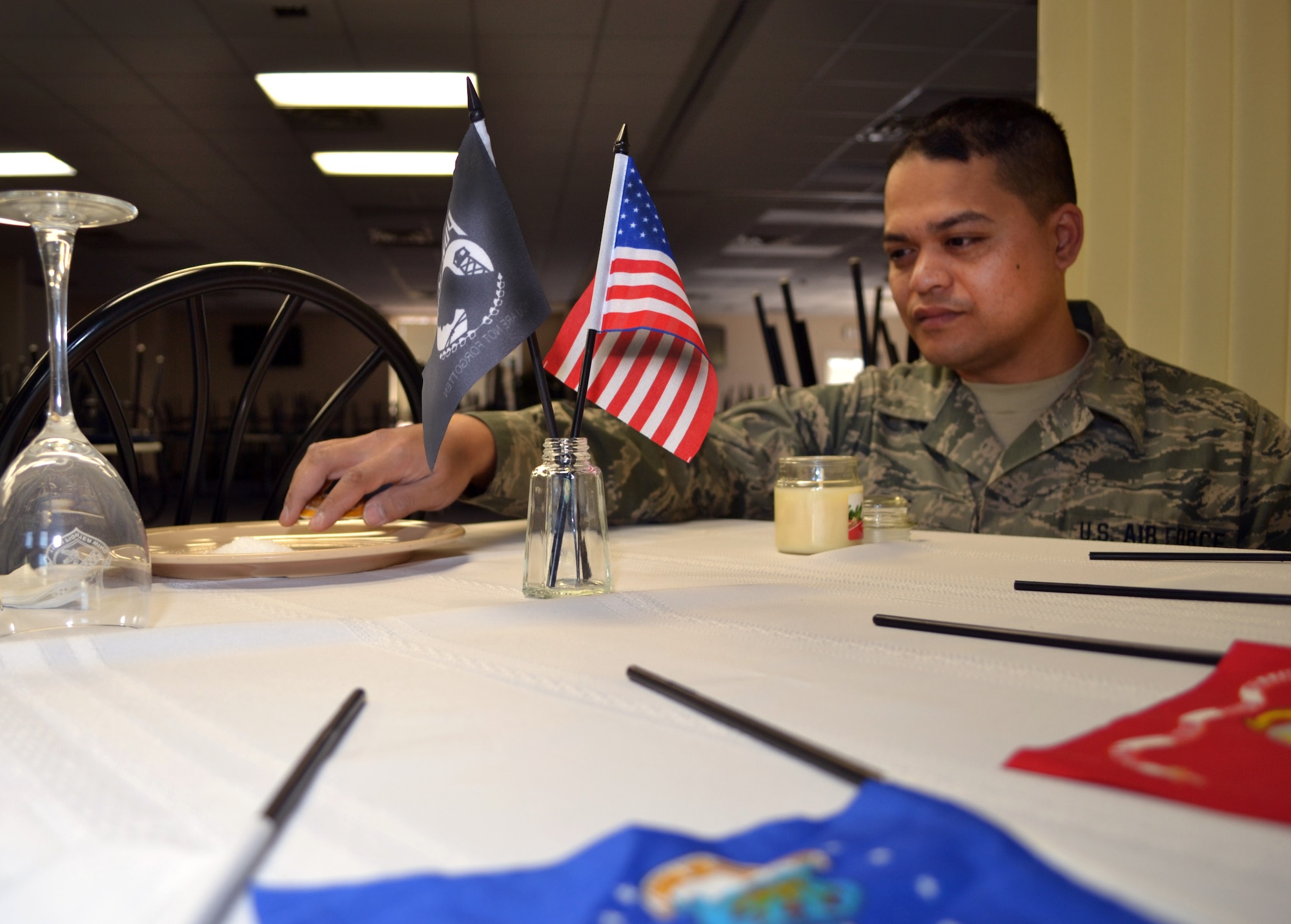 Senior Airman Alan Phe, of the 111th Force Support Squadron Service Flight, removes the lemon slice from the bread plate of the prisoners of war/missing in action (POW/MIA) table he created recently at Horsham Air Guard Station, Pennsylvania, Feb. 22, 2016. Commonly located in the dining areas of military installations, at ceremonies and at events, prior to Phe's assembly of the display, Horsham AGS did not have one on the installation. (U.S. Air Force photo by Tech. Sgt. Andria Allmond)