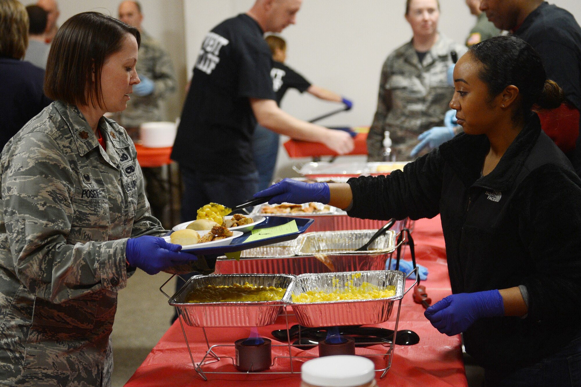 Maj. Faith Posey, 62nd Aerial Port Squadron commander, serves food to the families attending the Team McChord Deployed Family Dinner Feb. 19, 2016, at the Chapel Support Center on Joint Base Lewis-McChord, Wash. The 62nd APS took the lead on making this quarter’s event a success, along with help from the McChord Field Chapel staff and Team McChord leadership. (U.S. Air Force photo/Senior Airman Divine Cox)