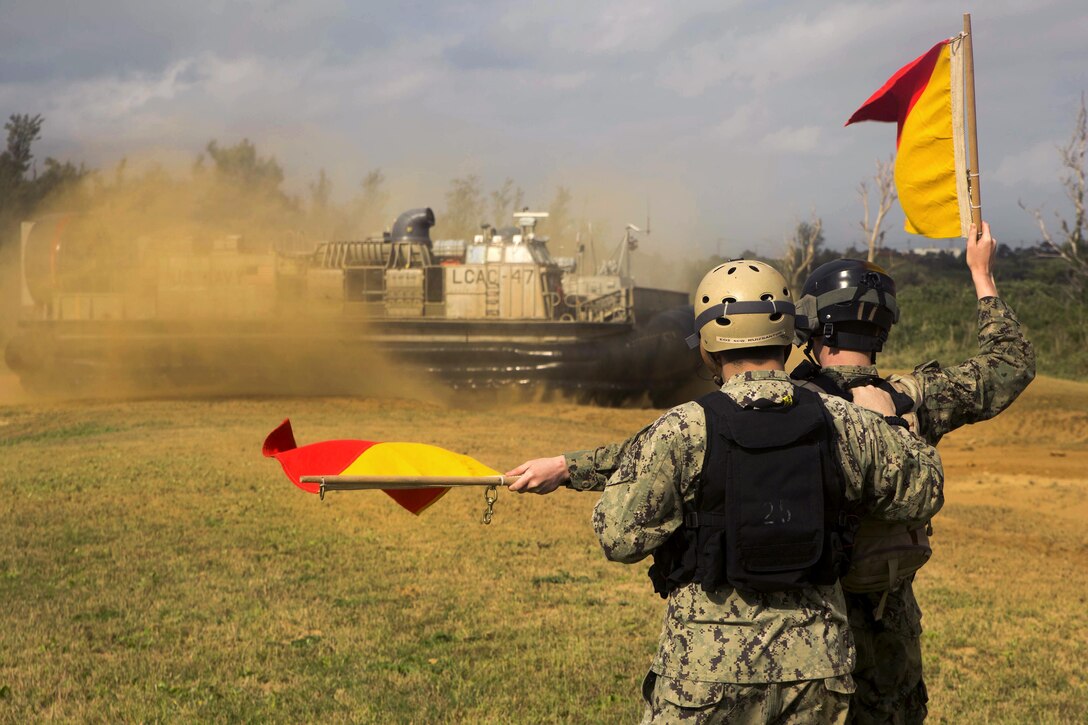 Navy Seaman Trent Burleigh, front, guides Landing Craft Air Cushioned 47 on Kin Blue Beach in Okinawa, Japan, Feb. 22, 2016. Burleigh is assigned to Naval Beach Unit 7. Sailors participated in a drill to test their ability to deploy fast help to support an embassy. Marine Corps photo by Cpl. Robert Williams Jr.