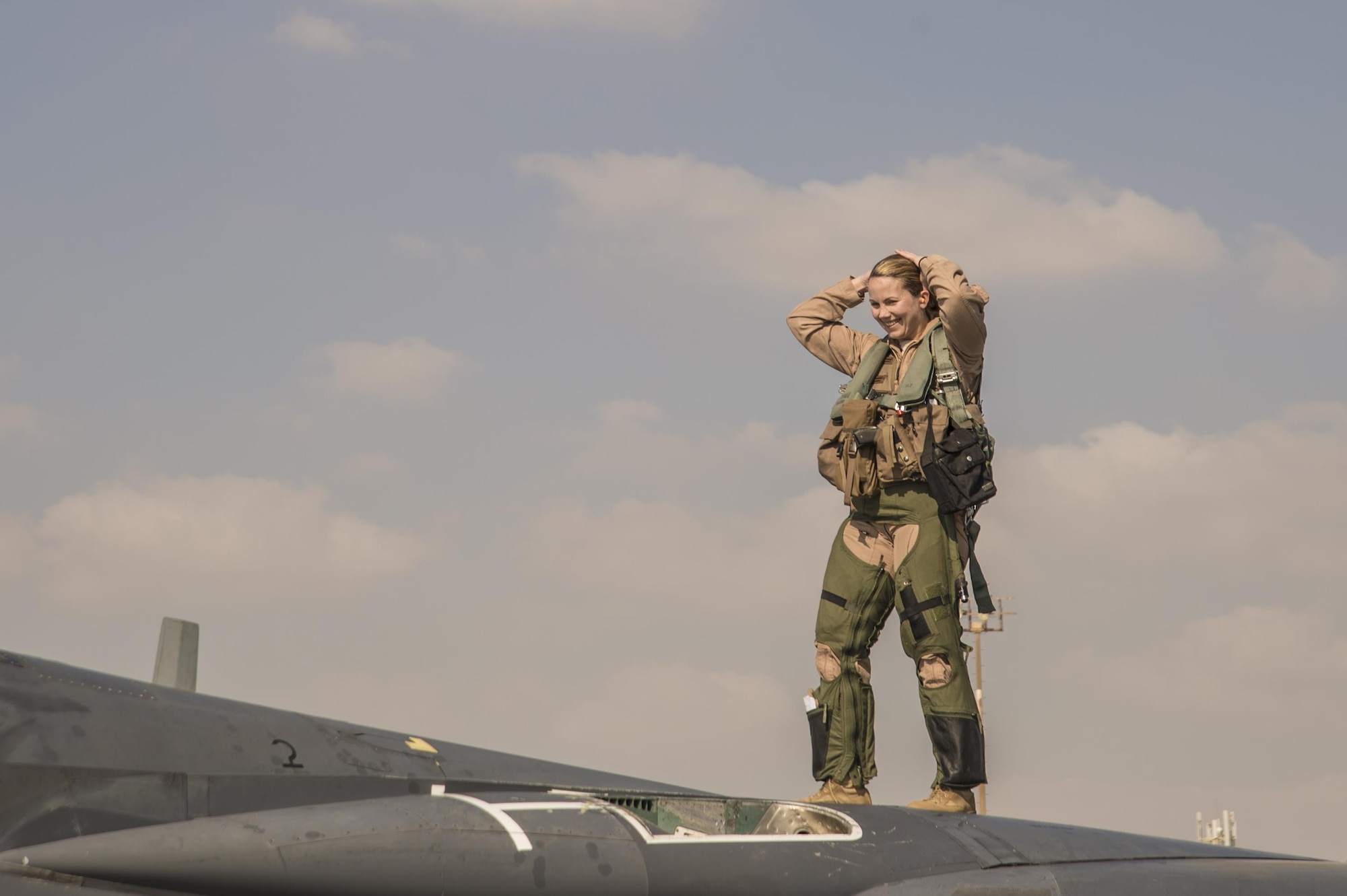 391st Expeditionary Fighter Squadron weapon systems officer, call sign Swat, stands on top of an F-15E Strike Eagle following a combat sortie at an undisclosed location in Southwest Asia, Feb. 13, 2016. Swat surpassed the 1,000 combat flight hour mark during the mission in support of Operation Inherent Resolve. (U. S. Air Force photo by Tech. Sgt. Frank Miller/Released)