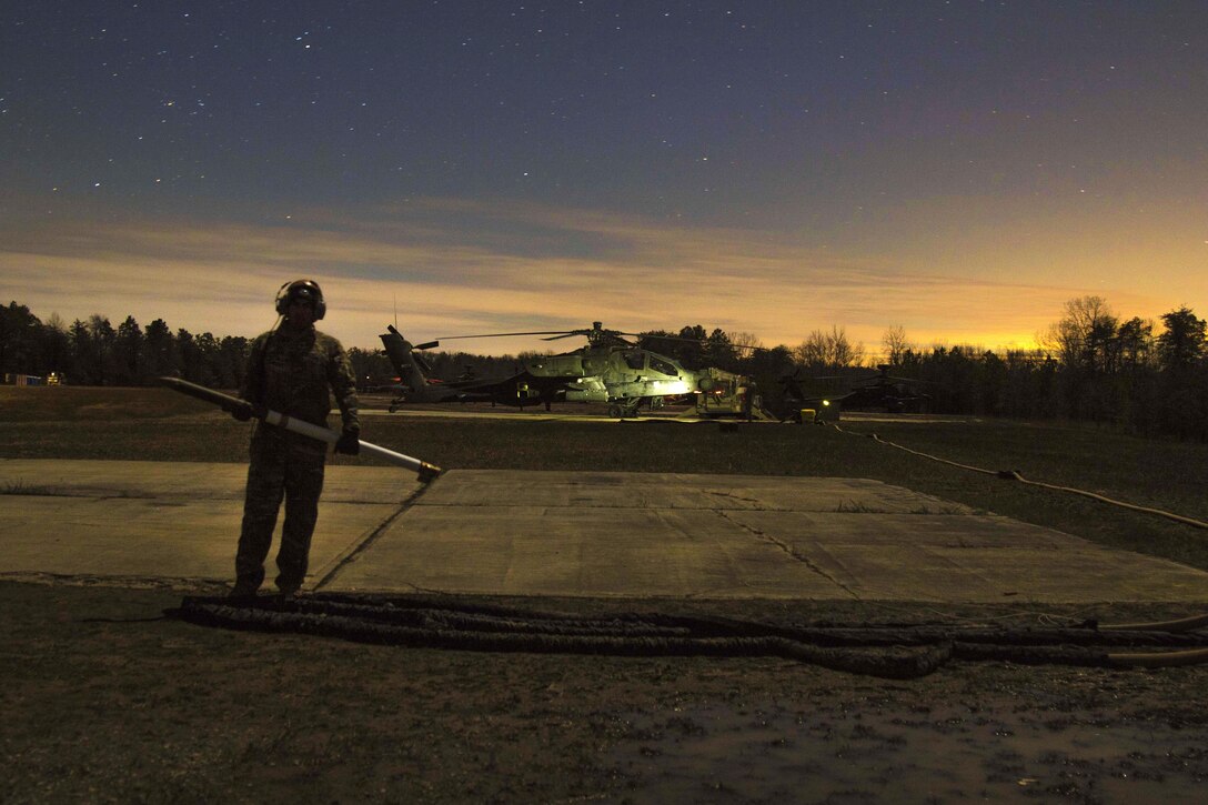 A soldier prepares to load a rocket onto an AH-64 Apache helicopter during an aerial gunnery exercise on Fort A.P. Hill, Va., Feb. 16, 2016. Army photo by Staff Sgt. Christopher Freeman