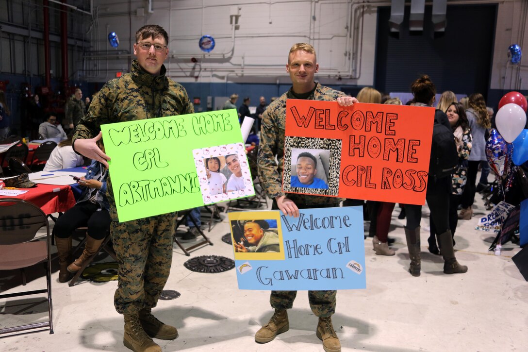 Sergeant William Cox, left, and Sgt. Dylan Stowers hold up sighs for fellow Marines during a homecoming ceremony at Marine Corps Air Station Cherry Point, N.C., Feb. 11, 2016. Marines and Sailors with Marine Tactical Electronic Warfare Squadron 3 returned to the air station after a six-month deployment in support of the United States Pacific Command combatant commander, Marine Aircraft Group 12, 1st Marine Aircraft Wing with EA-6B expeditionary electronic warfare capabilities. Cox is a electronic counter measure systems technician and Stowers is an advance automatic test equipment technician. (U.S. Marine Corps photo by Cpl. N.W. Huertas/Released)