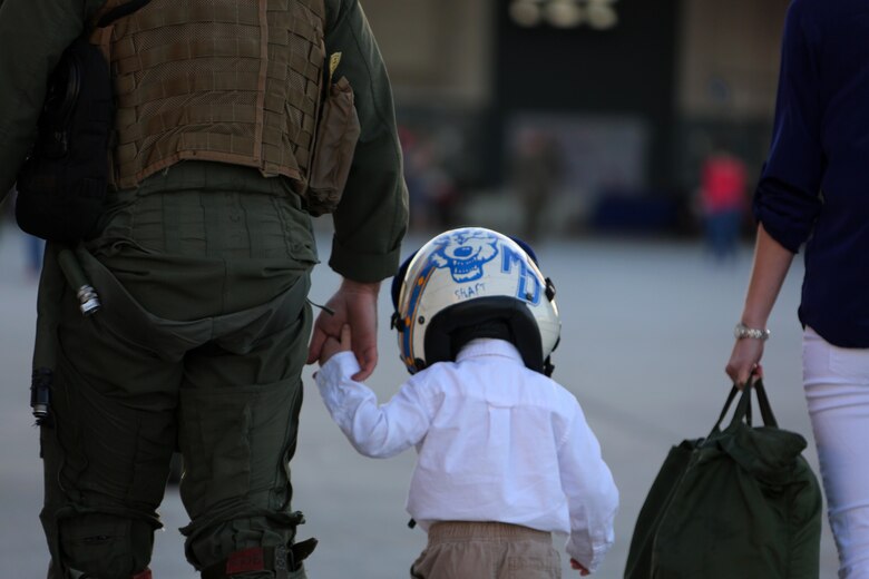 A Marine holds his sons hand during a homecoming ceremony at Marine Corps Air Station Cherry Point, N.C., Feb. 16, 2016. Marines and Sailors with Marine Tactical Electronic Warfare Squadron 3 returned to the air station after a six-month deployment in support of the United States Pacific Command combatant commander, Marine Aircraft Group 12, 1st Marine Aircraft Wing with EA-6B expeditionary electronic warfare capabilities. (U.S. Marine Corps photo by Cpl. N.W. Huertas/Released)