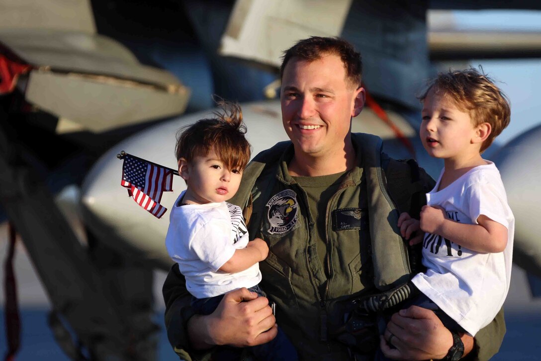 Captain Adam Chase holds his sons, Colin and Logan, during a homecoming ceremony at Marine Corps Air Station Cherry Point, N.C., Feb. 16, 2016. Marines and Sailors with Marine Tactical Electronic Warfare Squadron 3 returned to the air station after a six-month deployment in support of the United States Pacific Command combatant commander, Marine Aircraft Group 12, 1st Marine Aircraft Wing with EA-6B expeditionary electronic warfare capabilities. Chase is an embark action officer with the squadron. (U.S. Marine Corps photo by Cpl. N.W. Huertas/Released)