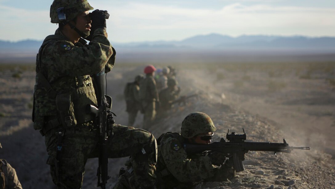 A rifleman assigned to Western Army Infantry Regiment, Japan Ground Self Defense Force, observes the impact area as several service members fire on simulated targets, during a live-fire platoon level assault, during Exercise Iron Fist 2016 at Marine Corps Air Ground Combat Center Twentynine Palms, Feb. 9, 2016. Iron Fist is an annual, bi-lateral training exercise between the Japan Ground Self Defense Force and Marines to strengthen warfighting capabilities in ship to shore operations.