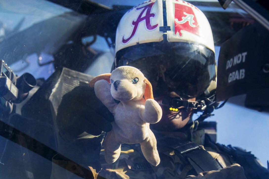 Army Chief Warrant Officer 2 Harold Johnson holds up "Fluffy," a doll given to him by his daughter for good luck, before participating in an aerial gunnery exercise on Fort A.P. Hill, Va., Feb. 18, 2016. Johnson, a pilot assigned to the 82nd Airborne Division’s 82nd Combat Aviation Brigade, 1st Attack Reconnaissance Battalion, carries the doll every time he flies, including when he flew in Afghanistan during a recent deployment. Army photo by Staff Sgt. Christopher Freeman 