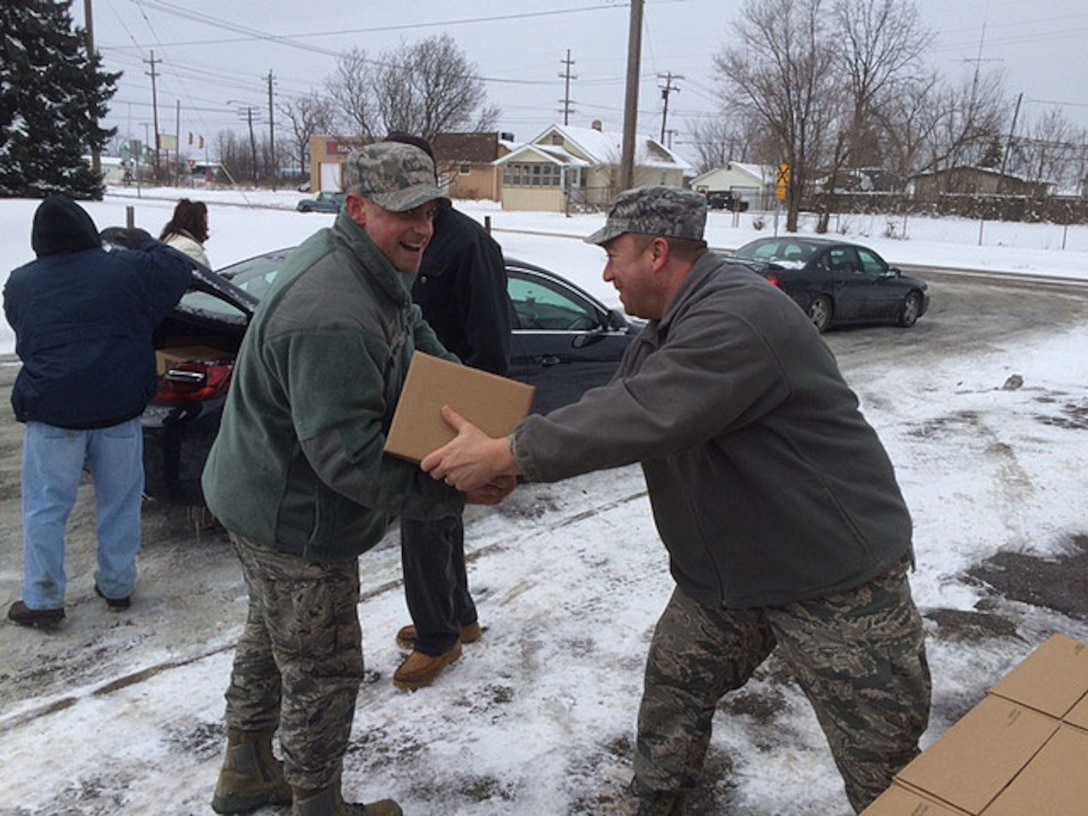 Staff Sgt. David Whitney (right) hands a box of bottled water to Staff Sgt. Parker Smith at Word Temple Church in Flint, Michigan, Feb. 10. Whitney and Parker are 339th Recruiting Squadron recruiters based in Flint. Due to massive amounts of lead found in Flint water, millions of bottles of water have been donated to the city and surrounding area since the crisis began. Residents are unable to drink or bathe in the water. The two recruiters have been assisting in the recovery every Wednesday by distributing water and filtration kits, and helping test for lead. (U.S. Air Force photo by Airman 1st Class Karl Fletcher)