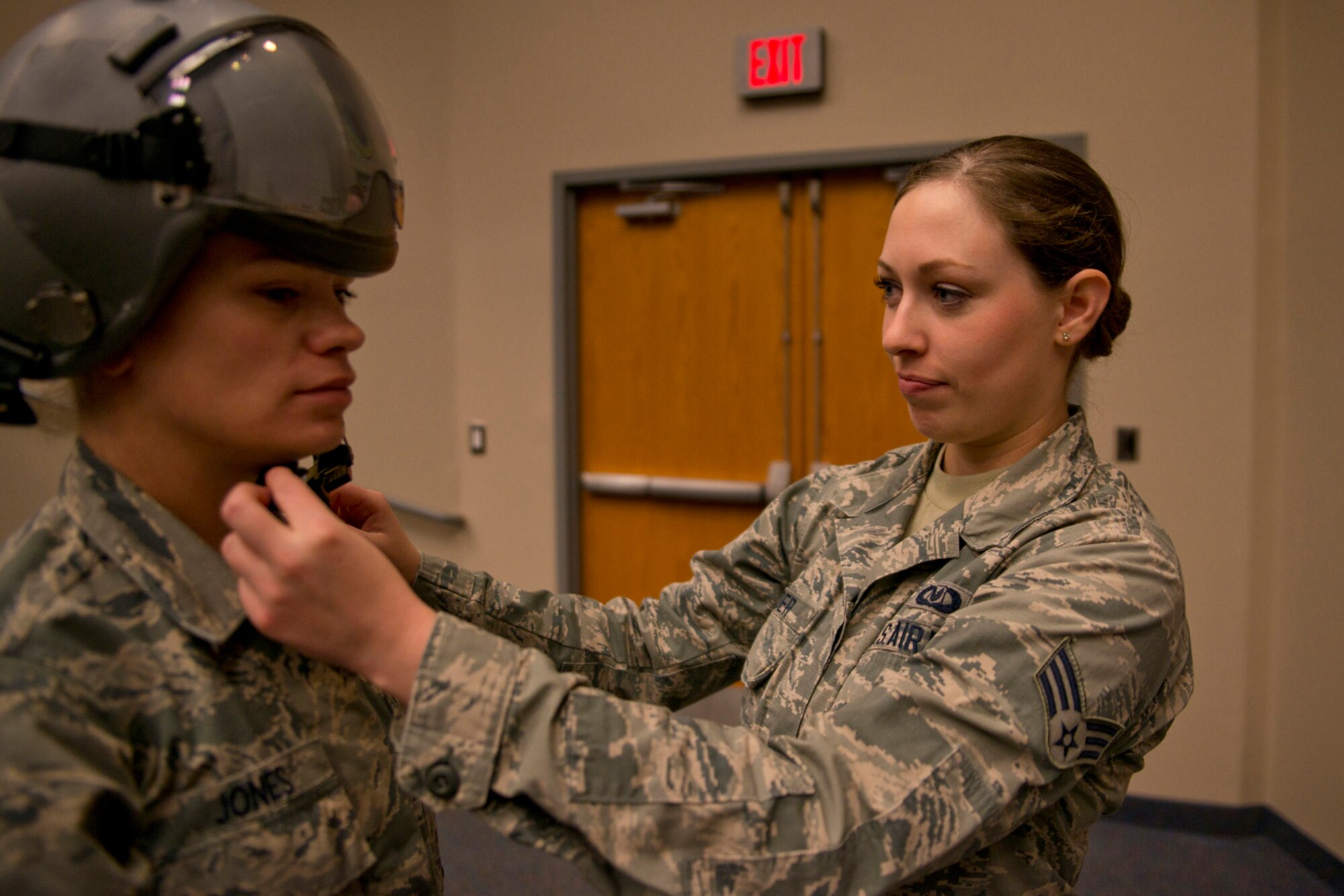 U.S. Air Force Reserve Senior Airman Bobbi Reader, aircrew flight equipment, 327th Airlift Squadron, assists Staff Sgt. Kimberly Jones, a fitness center specialist assigned to the 19th Force Support Squadron, with donning a helmet at Little Rock Air Force base, Ark., Feb. 19, 2016. Aircrew wear helmets to protect against small-arms fire, shrapnel, and injuries that may be caused by a rough ride, but helmets also house communication systems as well as components for Heads-up Display’s integration with vision equipment. (U.S. Air Force photo by Master Sgt. Jeff Walston/Released)   