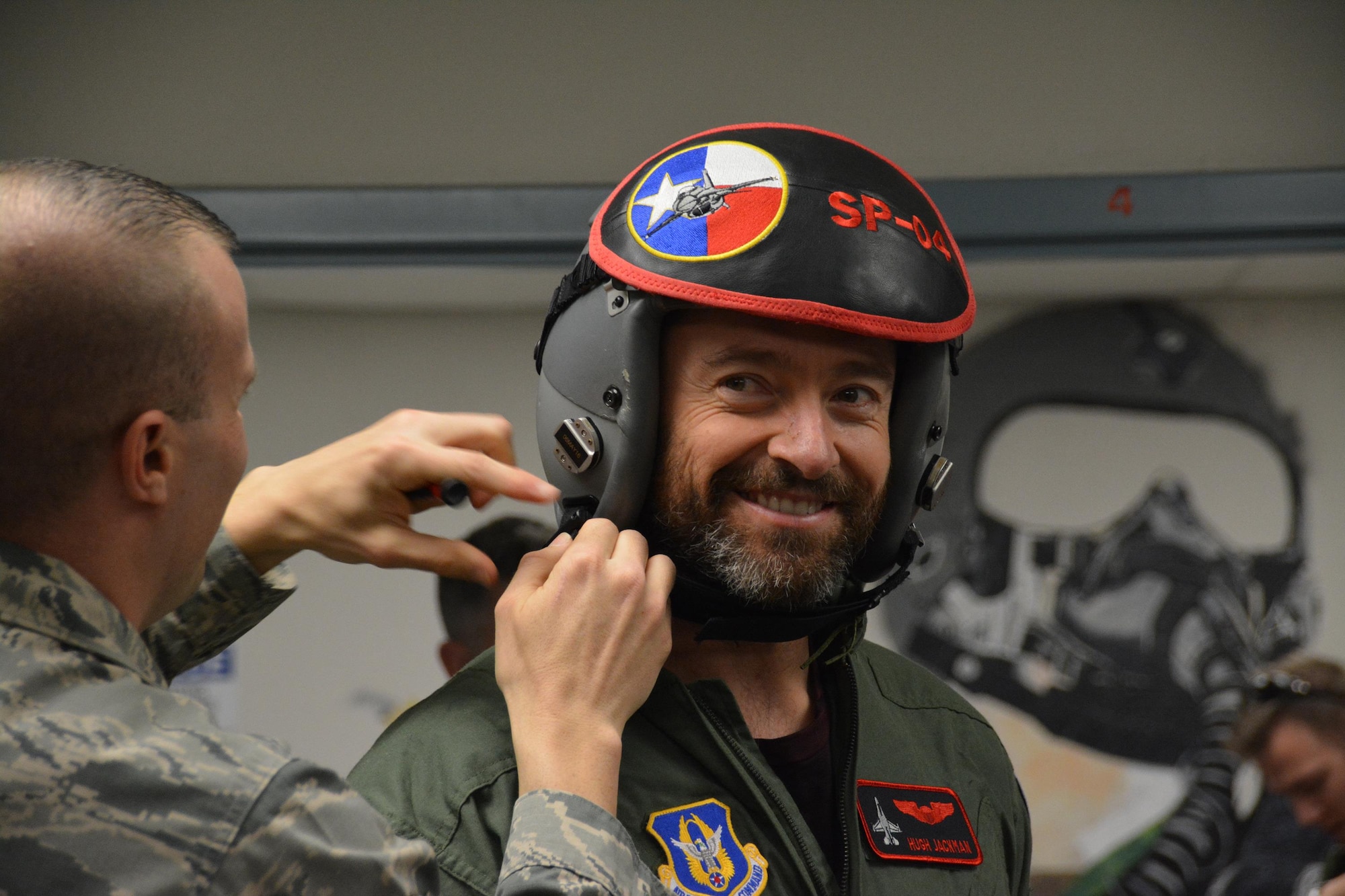 NAVAL AIR STATION FORT WORTH JOINT RESERVE BASE, Texas – Hugh Jackman, “Eddie the Eagle” star, smiles here while Master Sgt. Jonathan Gibson, 301st Operations Support Flight non-commissioned officer in charge of aircraft section, adjusts his helmet Feb. 19 in preparation for flight. Jackman flew in an Air Force Reserve F-16 Fighting Falcon for more than 45 minutes above North Texas. (U.S. Air Force photo by Staff Sgt. Samantha Mathison)
