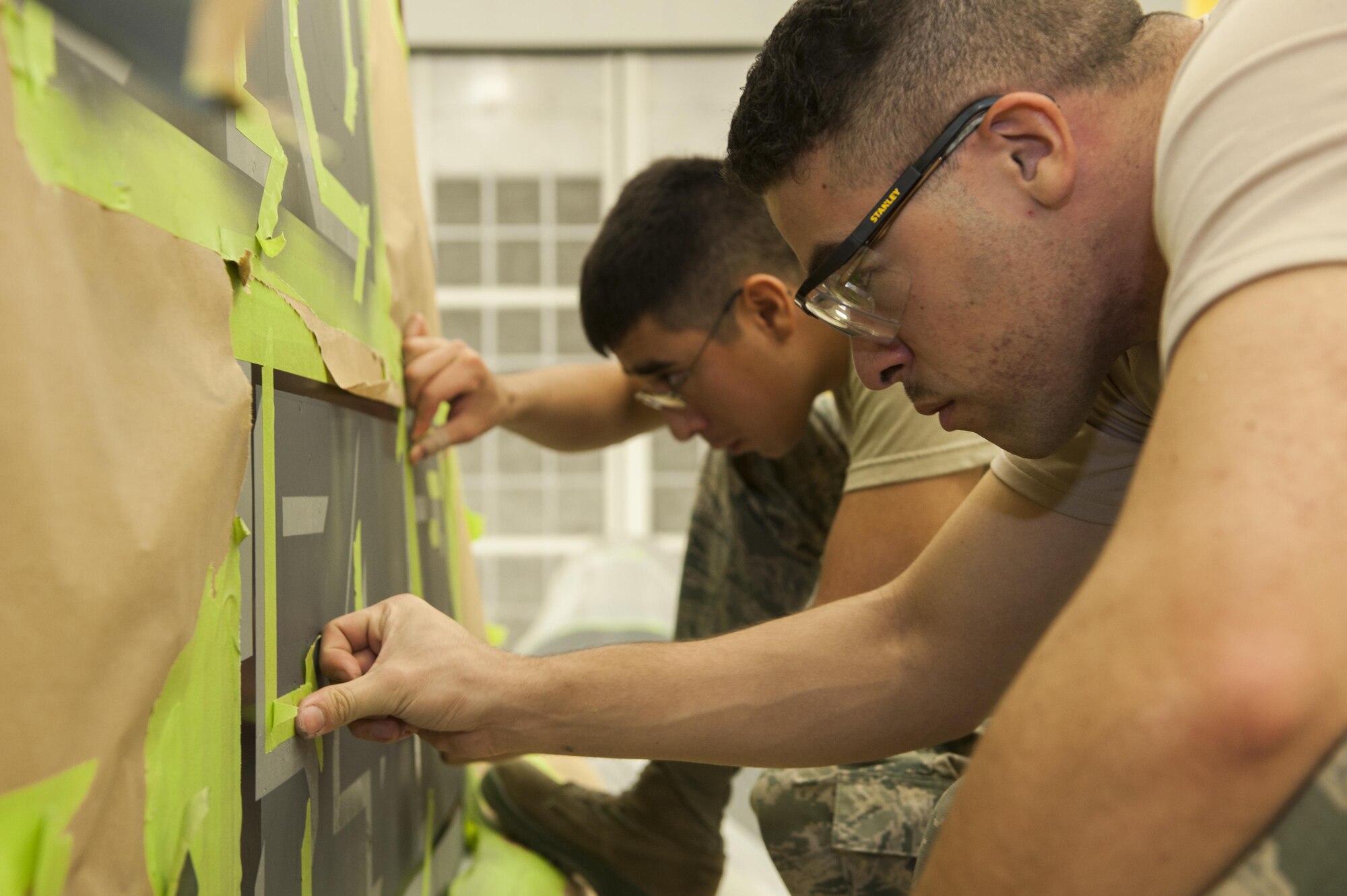 Airmen 1st Class Robert Rocha (left) and Ryan Magusiak, aircraft structural maintenance technicians with the 49th Maintenance Squadron, tape off the tail of the 54th Fighter Squadron’s F-16 Fighting Falcon flagship in preparation for painting at Holloman Air Force Base, N.M., Nov. 10, 2015. Corrosion control specialists stripped, primed and painted every flagship tail, replacing the Luke AFB symbol “LF” with Holloman’s symbol “HO.” (U.S. Air Force photo/Airman 1st Class Randahl J. Jenson)