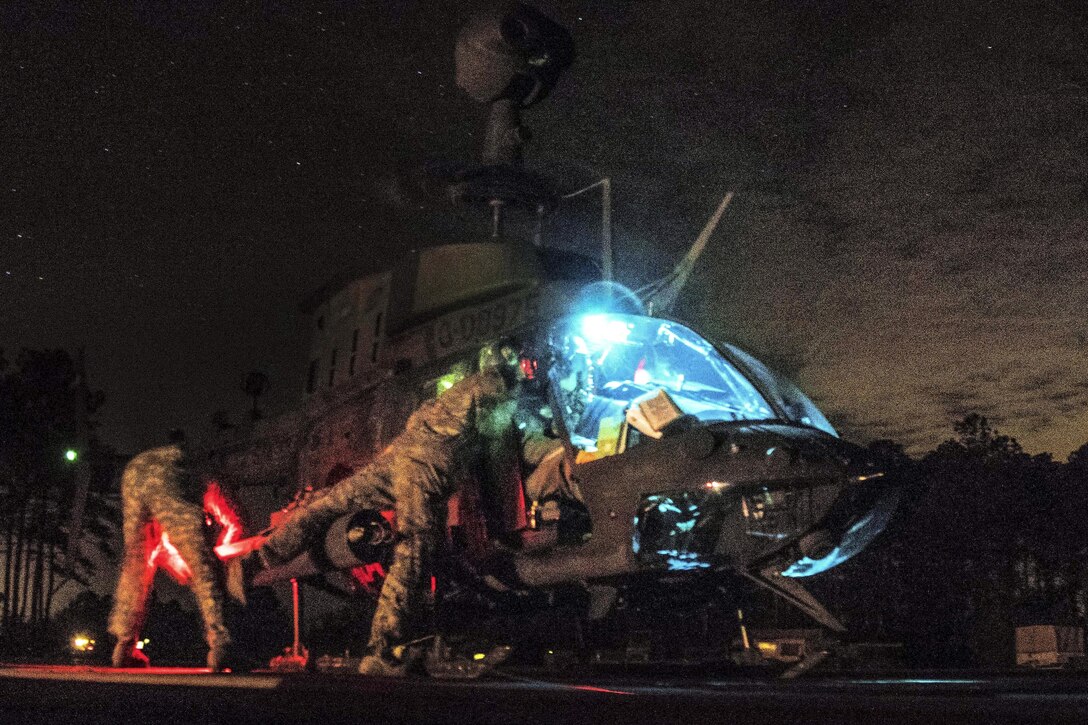 Troops load fuel and ammunition onto an OH-58 Kiowa Warrior helicopter before a night live-fire exercise on Marine Corps Outlying Field Atlantic, N.C., Feb. 8, 2016. The soldiers and pilots are assigned to the 82nd Airborne Division’s 17th Cavalry Regiment, 82nd Combat Aviation Brigade. Army photo by Staff Sgt. Christopher Freeman