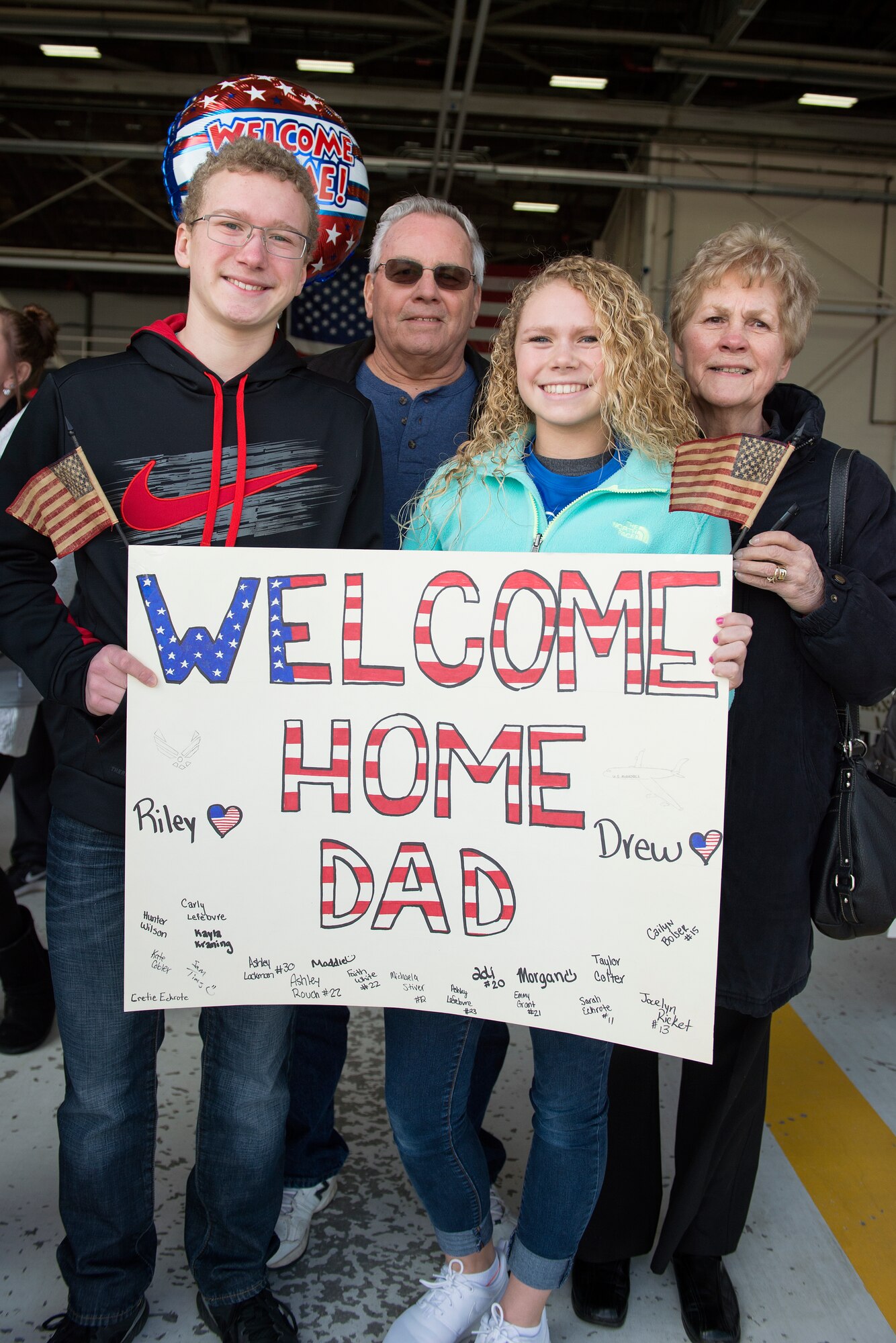 From left to right Drew, John, Riley and Diane Saddlemire hold a sign to welcome home Master Sgt. Eric Saddlemire, 434th Aircraft Maintenance Squadron crew chief, prior to his arrival at Grissom Air Reserve Base, Ind., Feb. 7, 2016. In addition to family members, other Airmen and leadership from Grissom stood by to greet the returning deployers after a 4-month deployment to Southwest Asia in support of Operation Inherent Resolve. (U.S. Air Force photo/Tech. Sgt. Benjamin Mota)