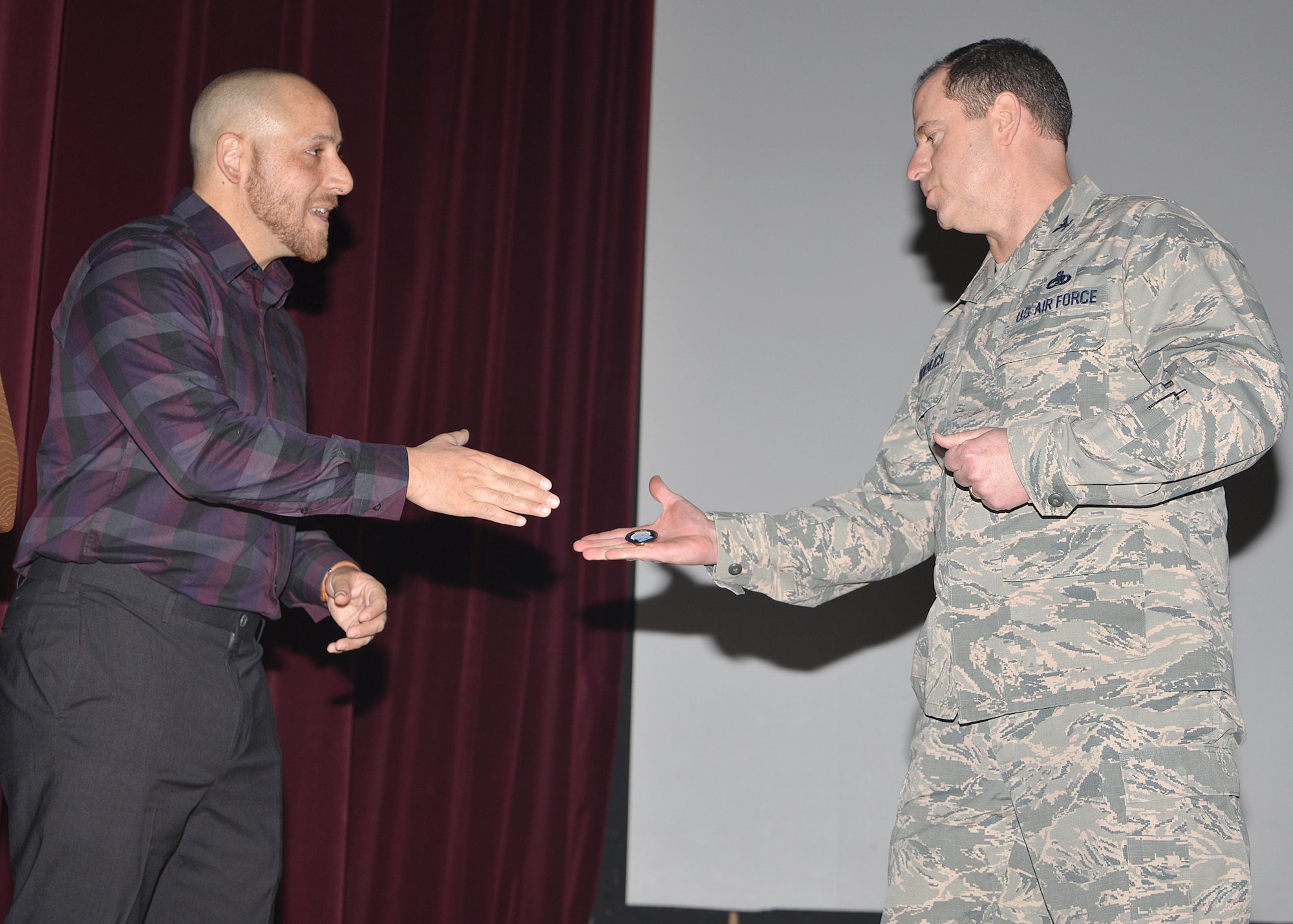 Col. Eric Froehlich, 377th Air Base Wing commander, gives a coin to mental health advocate Kevin Hines. Hines shared his story of struggling with mental health issues, and his miraculous survival of a suicide attempt  during multiple presentations Feb. 22-23 at the Base Theater. (Photo by Todd Berenger)

