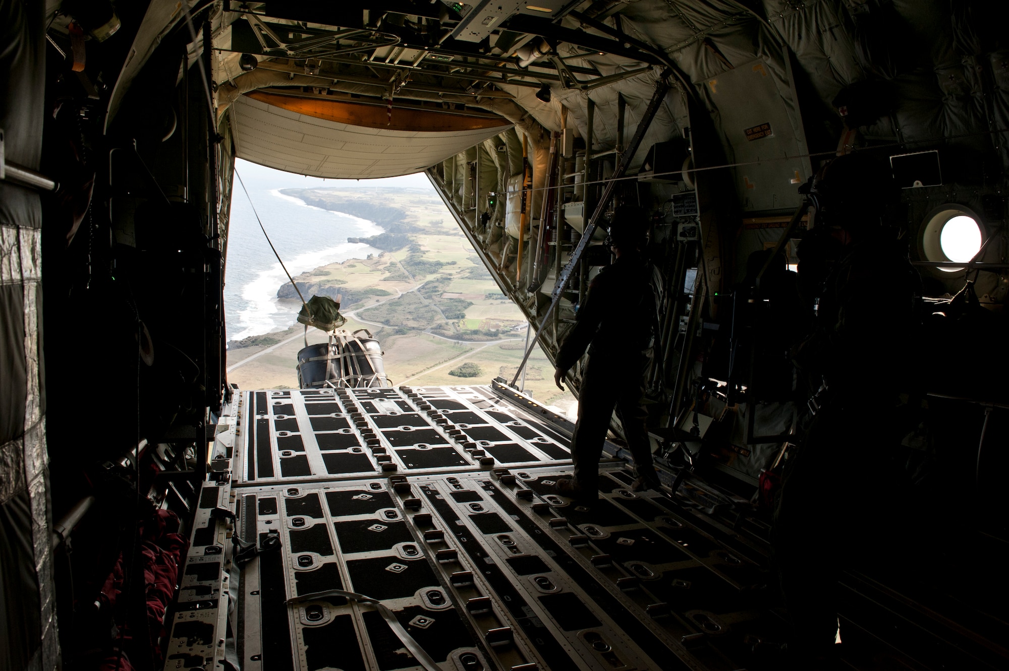 U.S. Air Force Senior Airman Zach Harmon, 17th Special Operations Squadron MC-130J Commando II loadmaster, releases a cargo delivery system over a drop zone during a training exercise Feb. 17, 2016, Okinawa, Japan. Harmon and other 17th SOS Jackals conducted a quick-reaction, full-force sortie that tested the unit's ability to safely execute a five-ship formation flight, cargo drops, short runway landings, and takeoffs, and helicopter air-to-air refueling. (U.S. Air Force photo by Senior Airman Peter Reft)