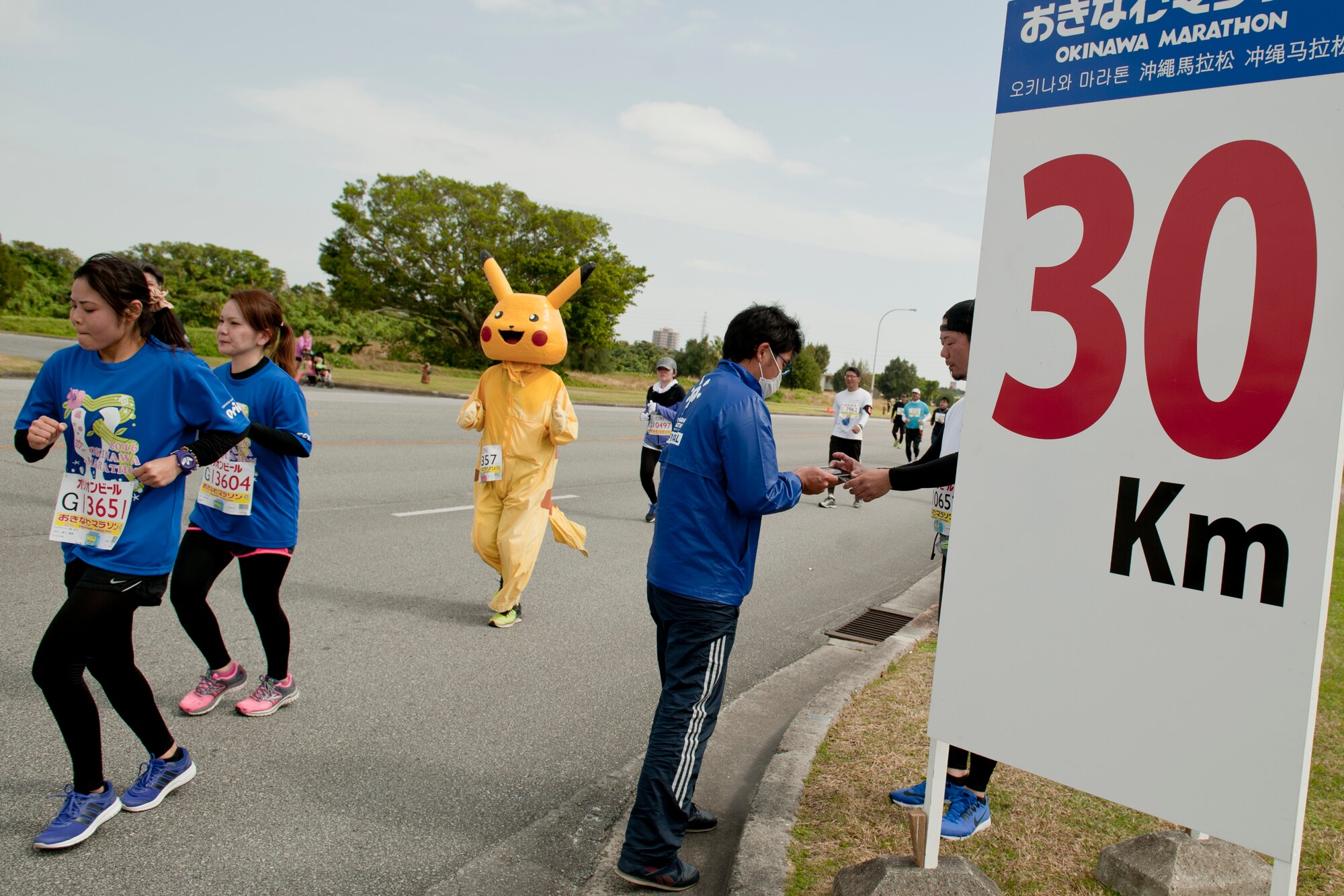 Runners pass the 30-kilometer mark during the Okinawa Marathon Feb. 21, 2016 at Kadena Air Base, Japan. Marathon runners dressed in a wide variety of costumes, including popular culture figures, merchandise, food, anime characters and superheroes. (U.S. Air Force photo by Senior Airman Peter Reft)