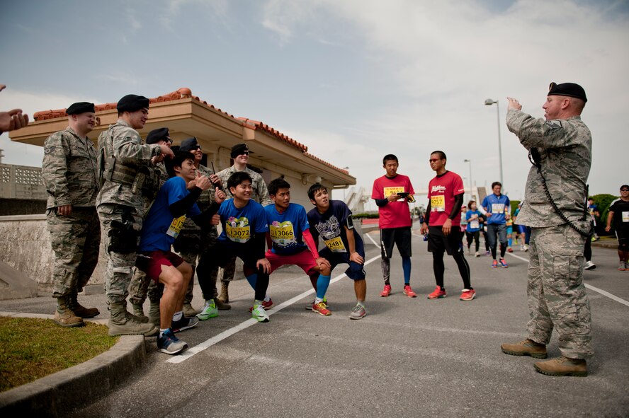 Runners take group photos with 18th Security Forces Squadron Airmen during the Okinawa Marathon Feb. 21, 2016 at Kadena Air Base, Japan. 18th SFS members provided traffic management on base and ensured the safety for runners. (U.S. Air Force photo by Senior Airman Peter Reft)