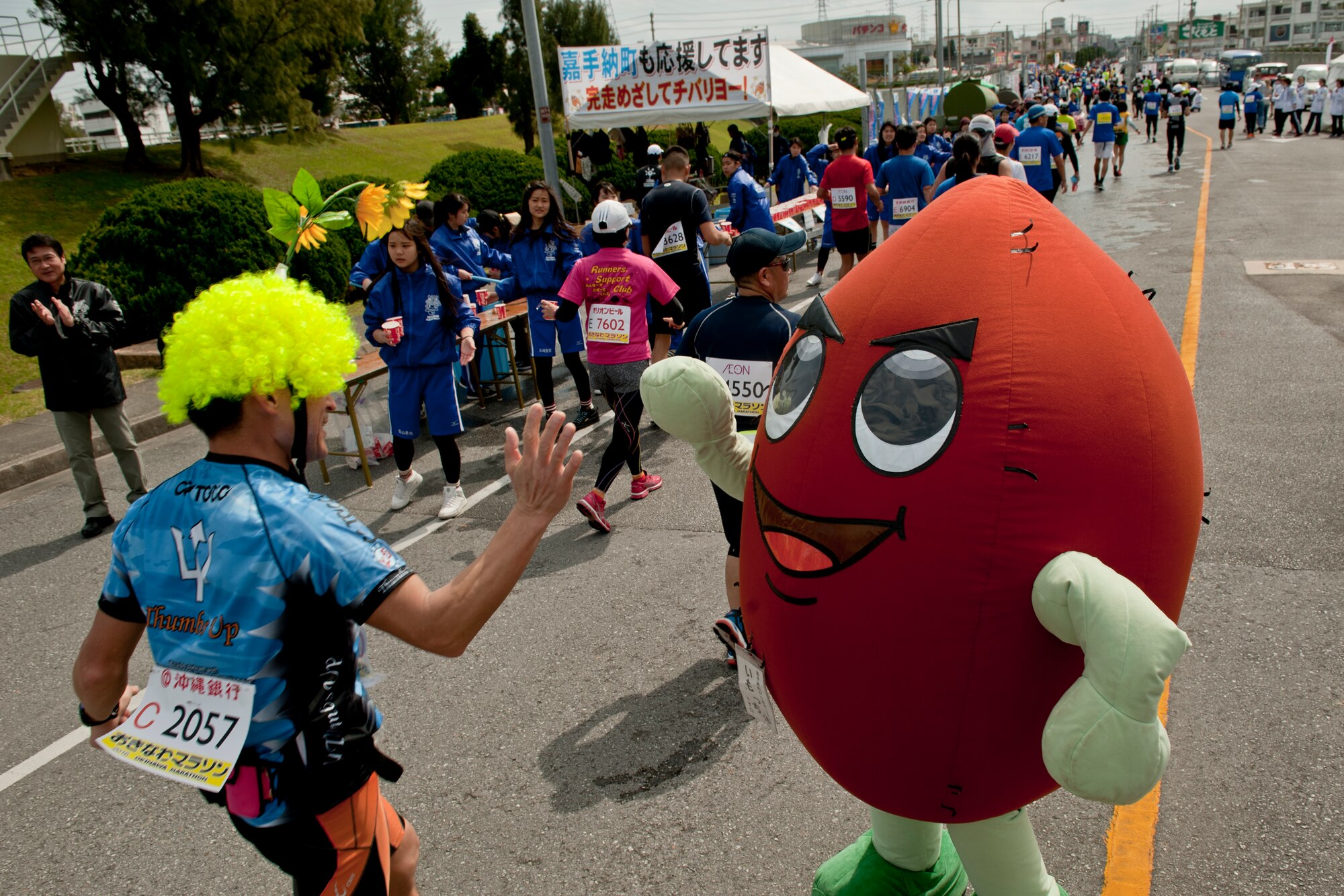 Runners pass a cheer and water station during the Okinawa Marathon Feb. 21, 2016 at Kadena Air Base, Japan. Kadena hosted a two-kilometer section of the marathon route, providing cheer stations, water stations and medical support. (U.S. Air Force photo by Senior Airman Peter Reft)