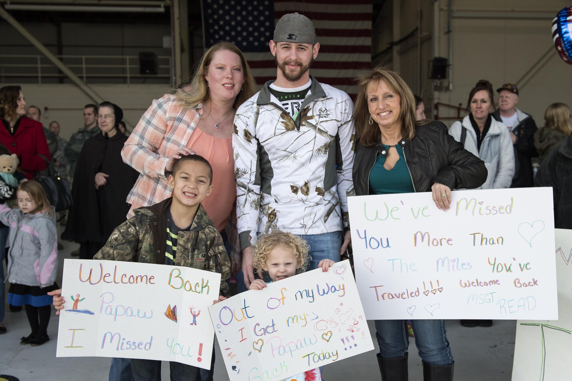 From left to right Sabra, Chris and Tammy Reed, stand behind Esme and Chaise Case with signs to welcome home Master Sgt. Chris Read, 434th Aircraft Maintenance Squadron crew chief, prior to his arrival at Grissom Air Reserve Base, Ind., Feb. 7, 2016. Grissom uses a variety of resources to help families reunite after deployments. (U.S. Air Force photo/Tech. Sgt. Benjamin Mota) 